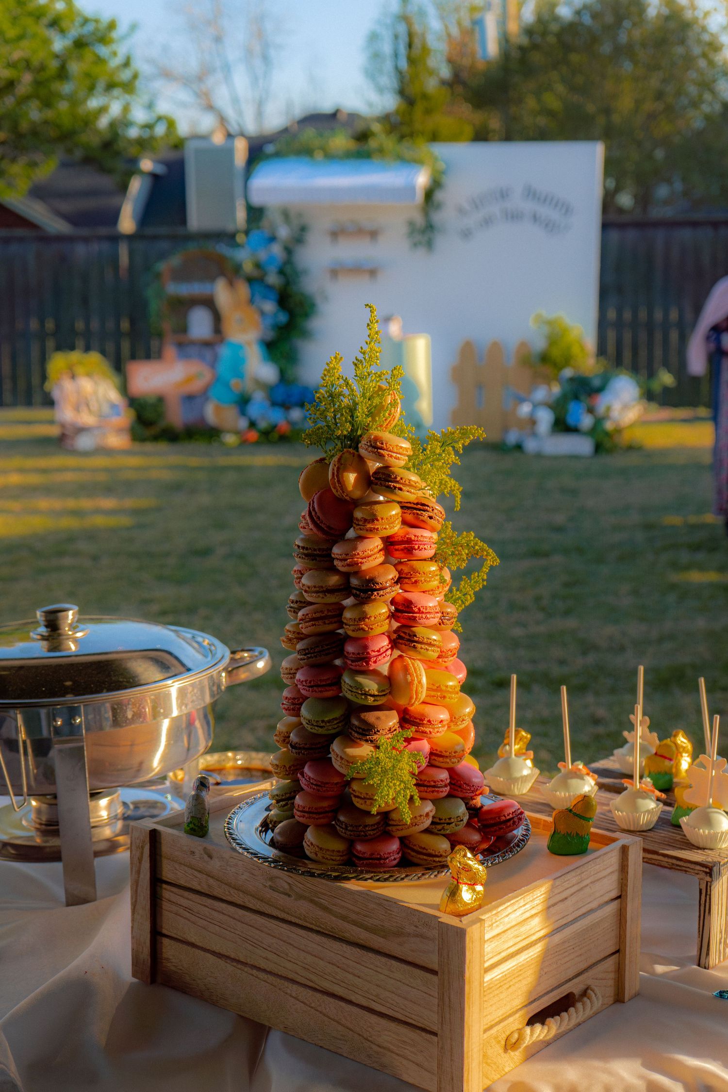Colorful macaron tower centerpiece at an outdoor baby shower dessert table.