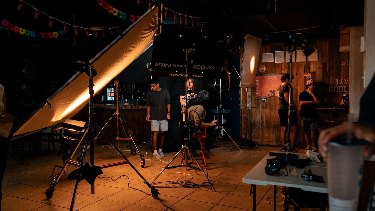 Behind-the-scenes film production setup with professional lighting equipment and crew members in a dark studio.