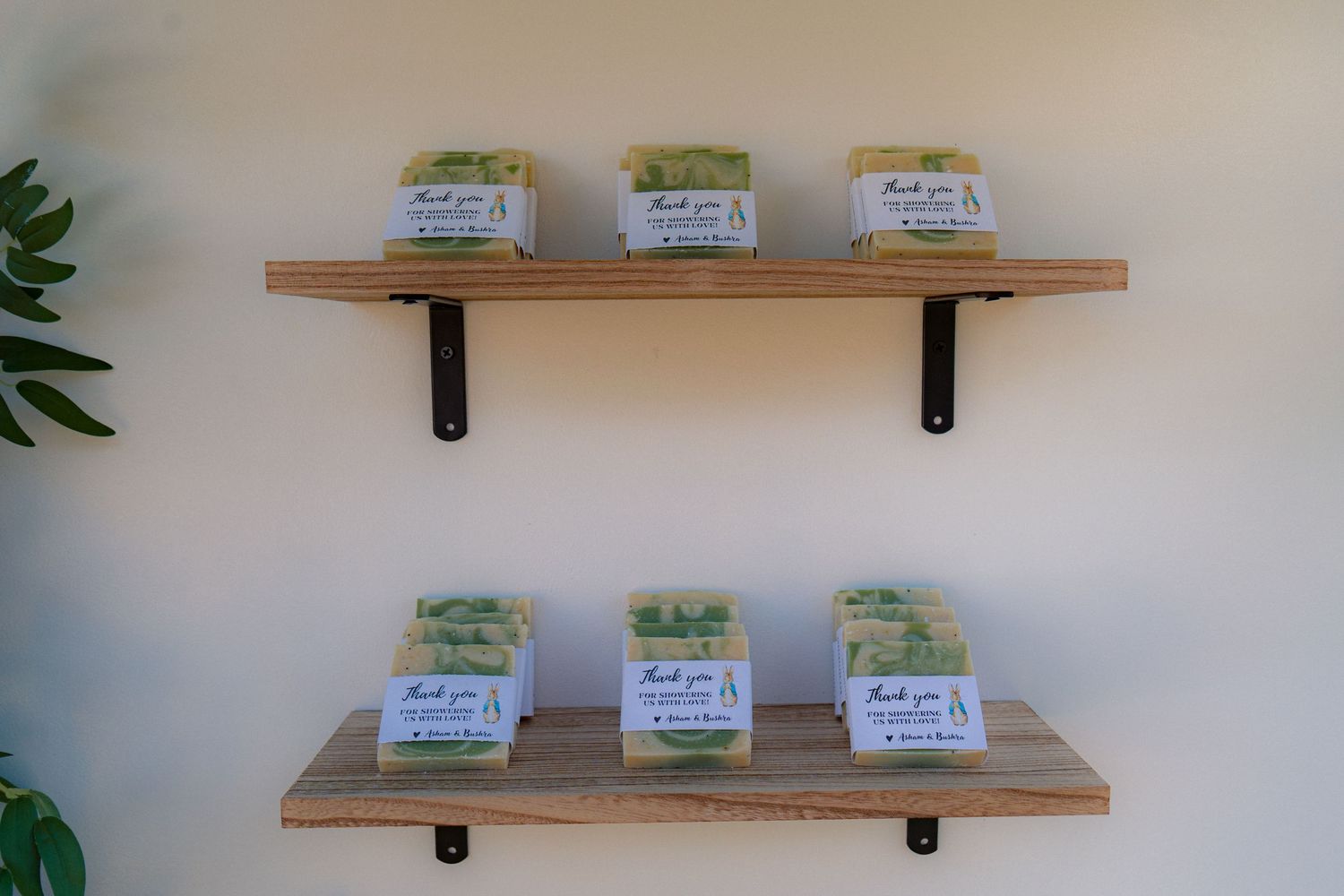 Two wooden wall shelves displaying green thank you gift favors at a Peter Rabbit baby shower.