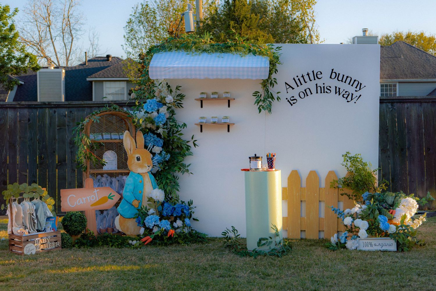 Peter Rabbit themed baby shower backdrop with bunny decor and a little bunny is on his way sign.