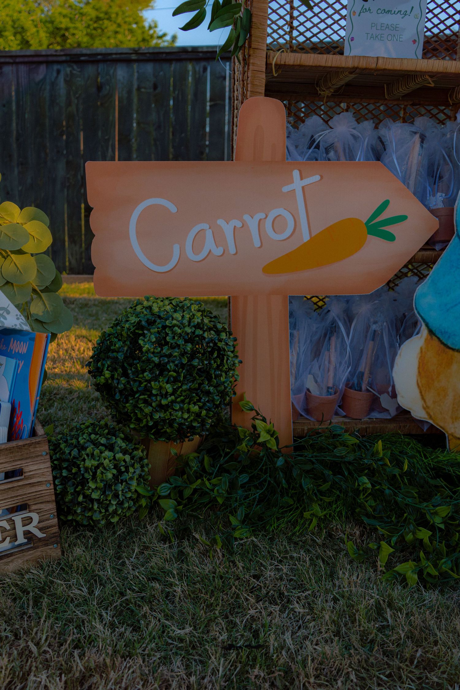 Decorative orange carrot directional sign in a garden-themed baby shower display.