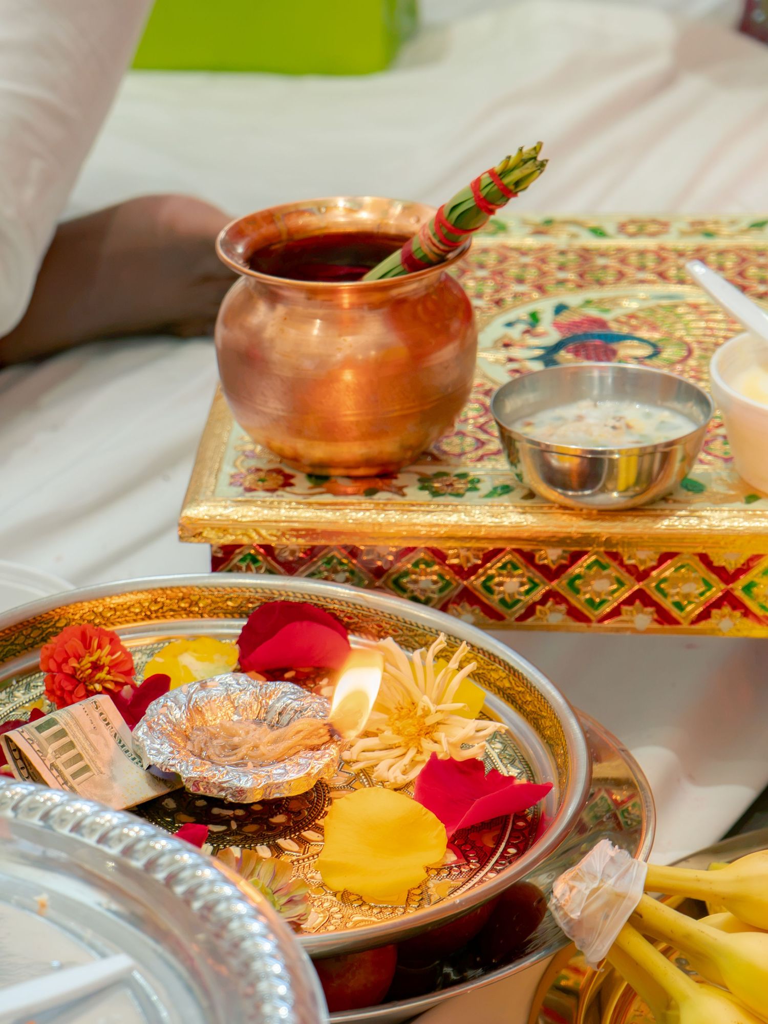 Hindu puja thali with diya, flowers, copper kalash, and decorated tray for religious ceremony.