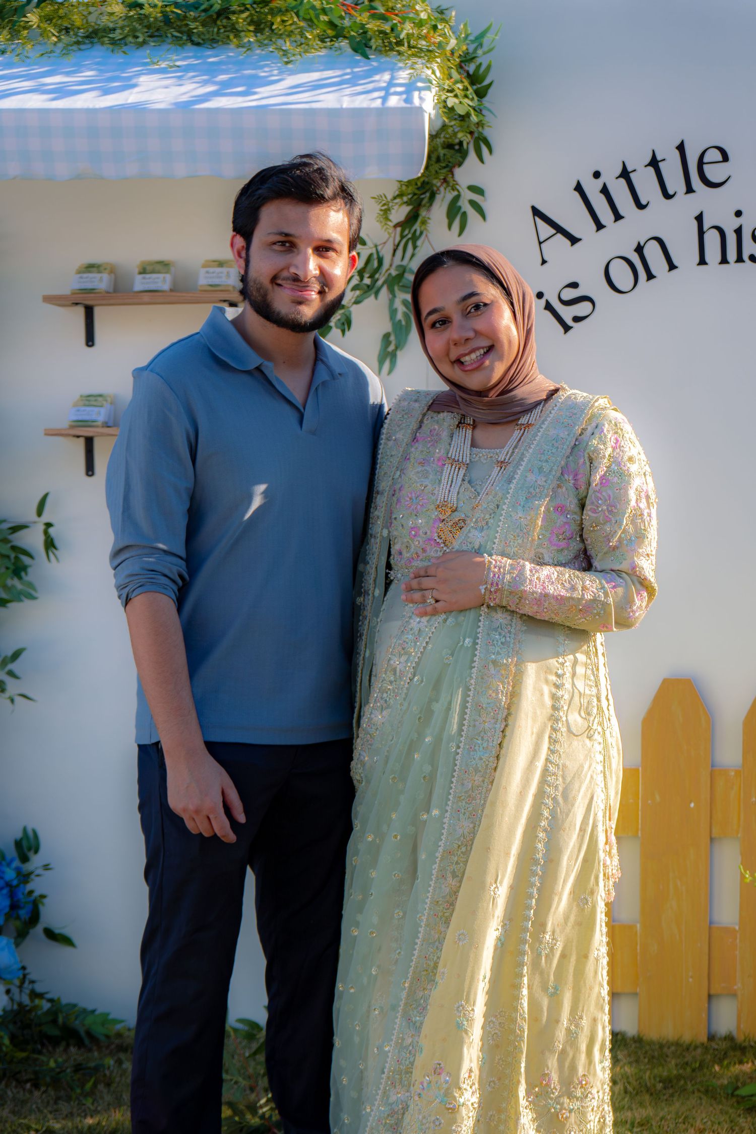 Couple smiling together at outdoor Peter Rabbit themed baby shower celebration in warm sunlight.
