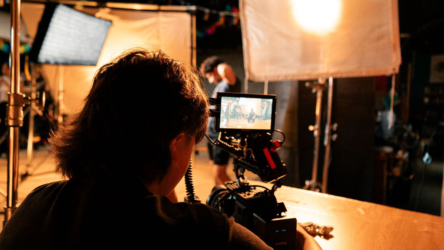 Cinematographer operating a professional camera rig on a film set with bright studio lighting.