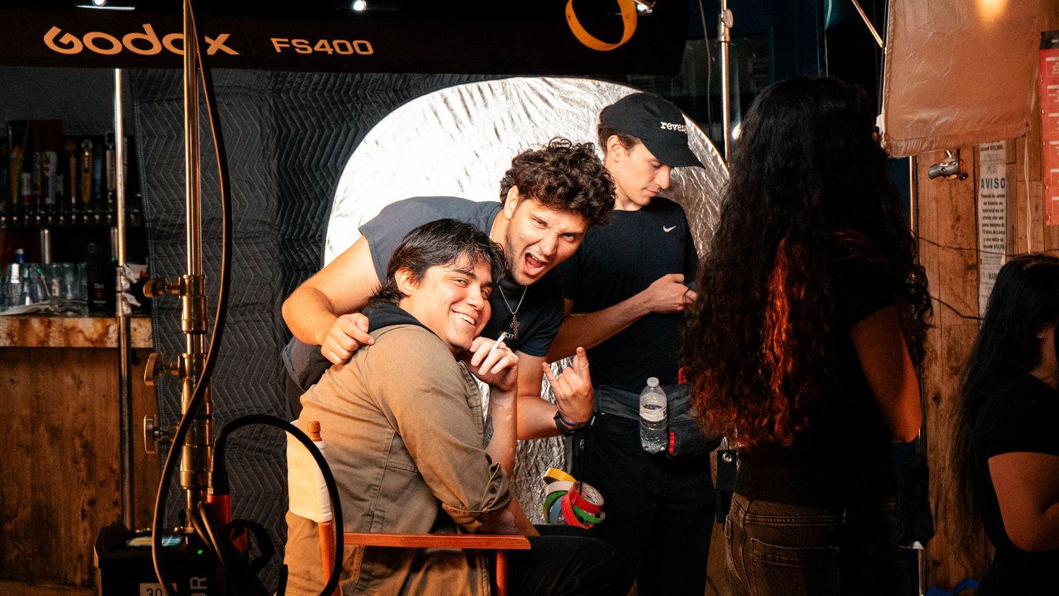 Behind-the-scenes photo shoot with crew members laughing and posing in front of a Godox FS400 lighting setup.