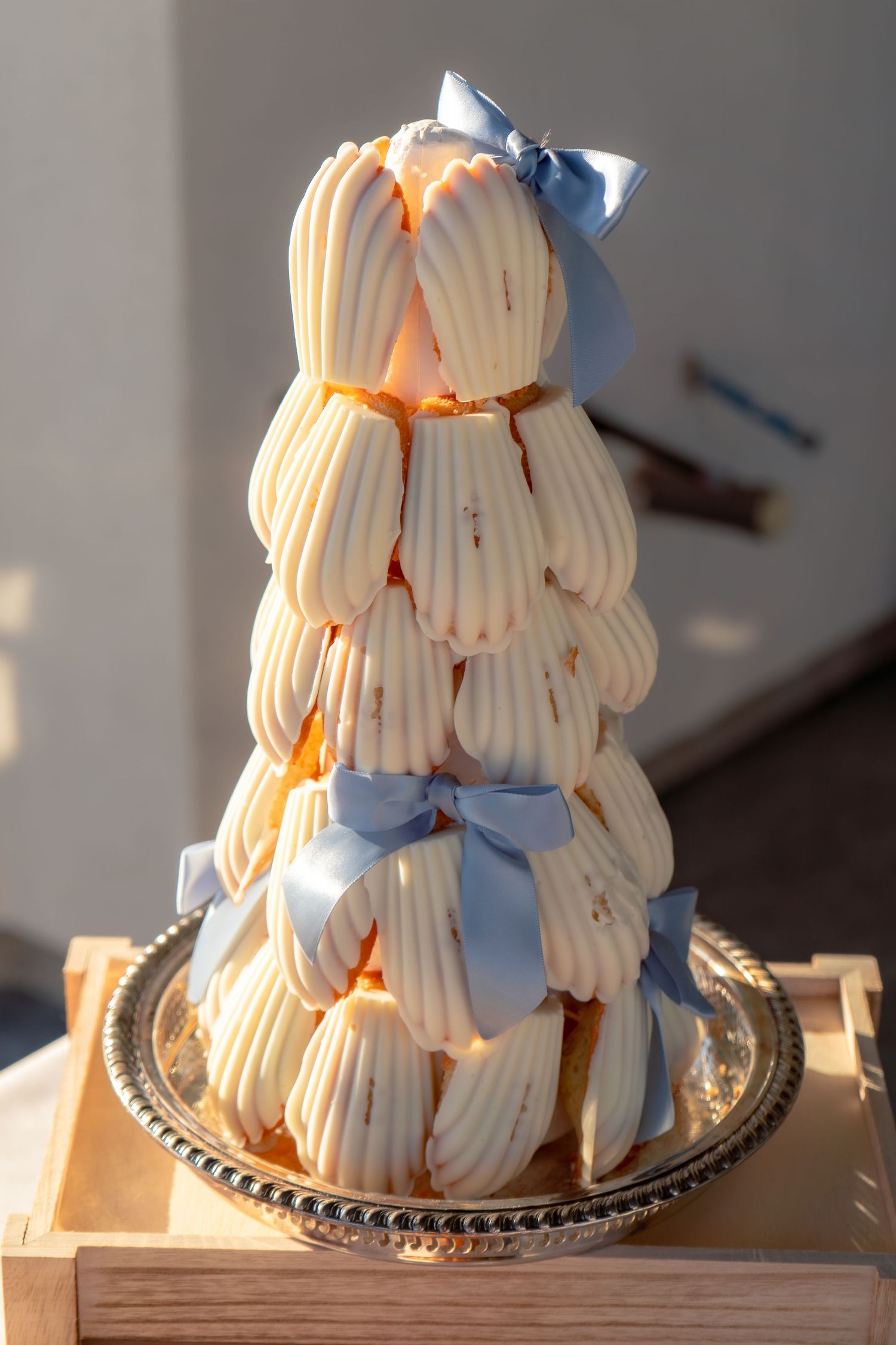 Elegant tower of cream puffs adorned with blue satin bows on a silver tray.