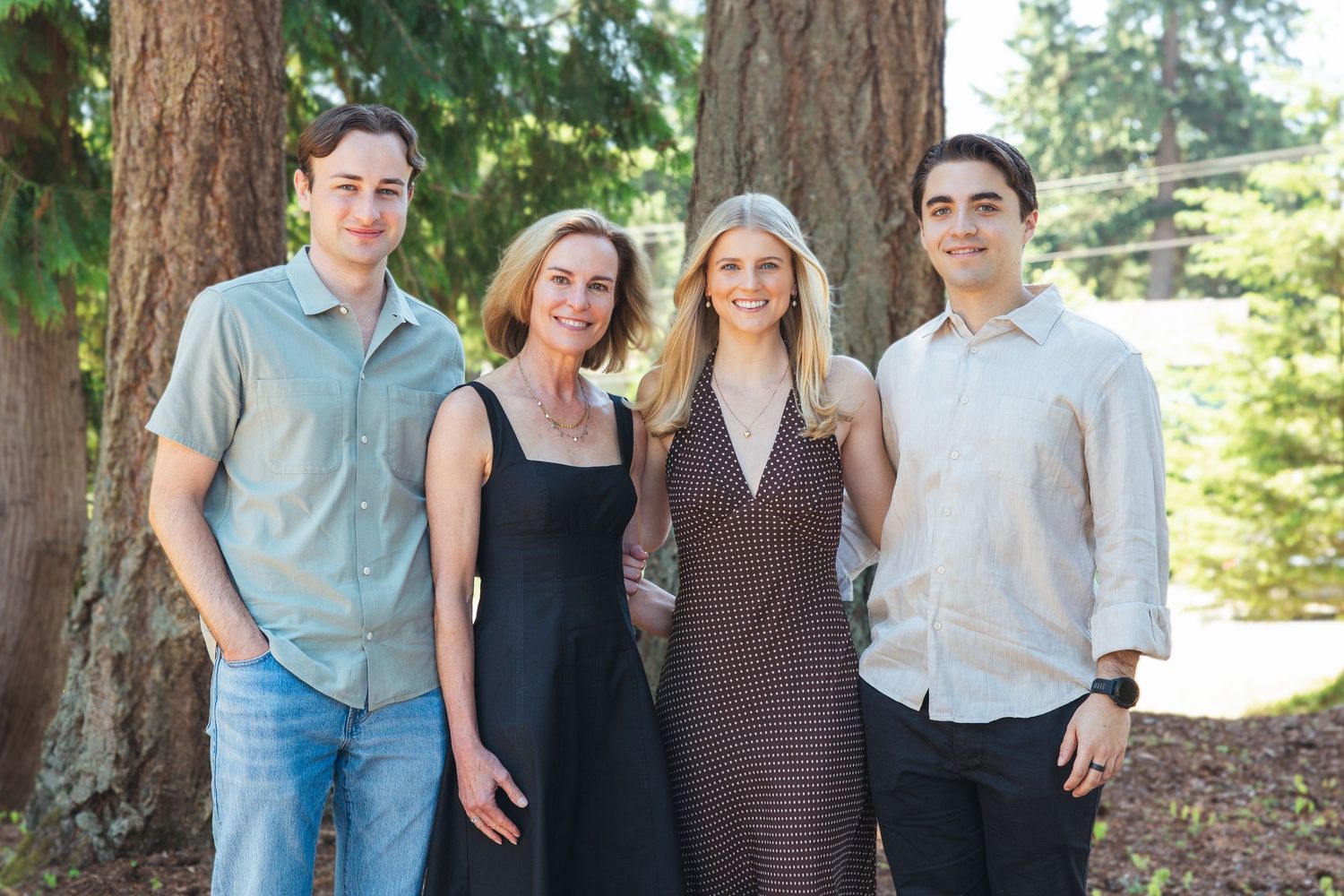Four family members posing together in a wooded park setting.