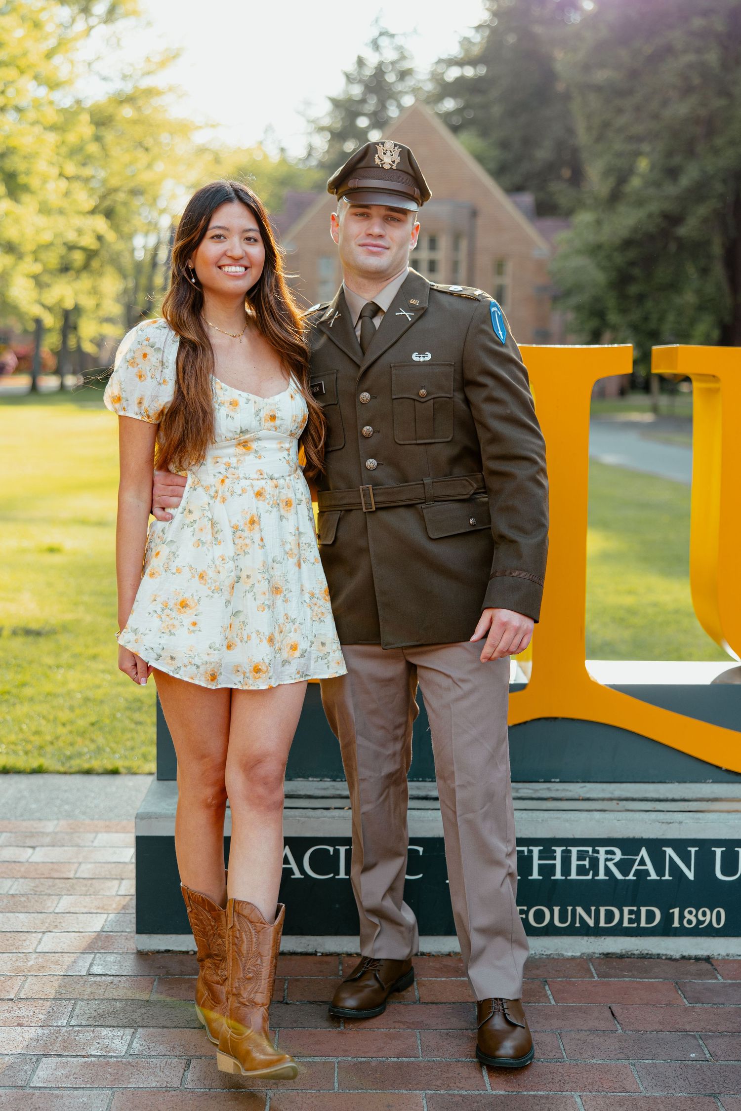 Couple posing at Pacific Lutheran University founded 1890, man in military uniform, woman in floral dress and cowboy boots.