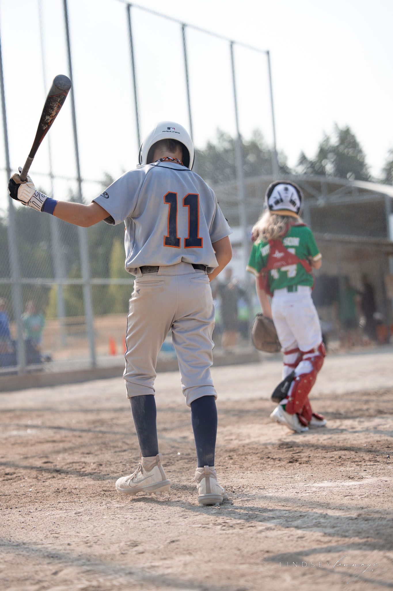 Youth baseball player number 11 in gray Knights uniform stands at bat with catcher behind home plate.