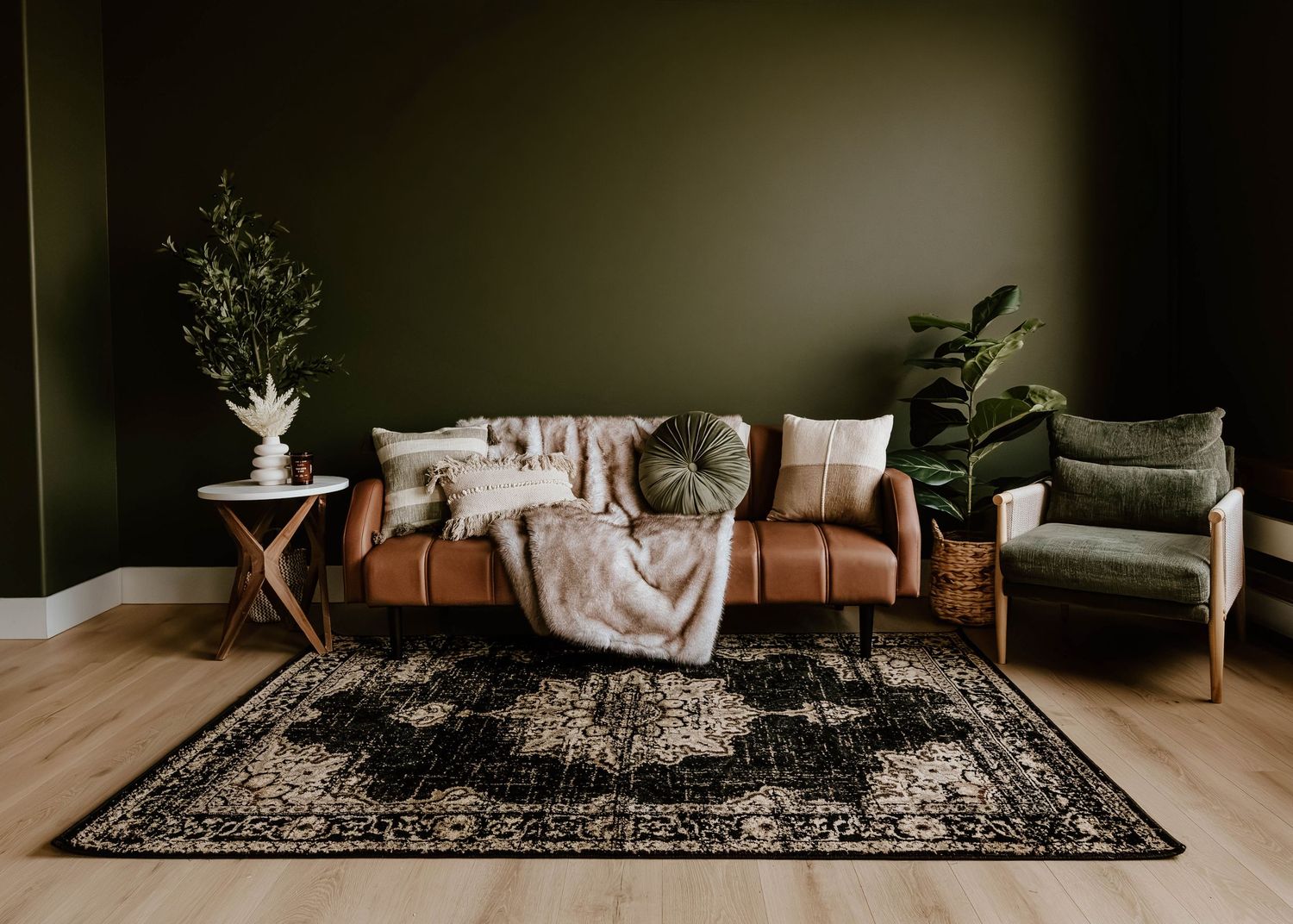 Styled seating area with a vintage sofa, accent chairs, greenery, and a patterned rug inside Everwild Collective Studio in Spokane, WA