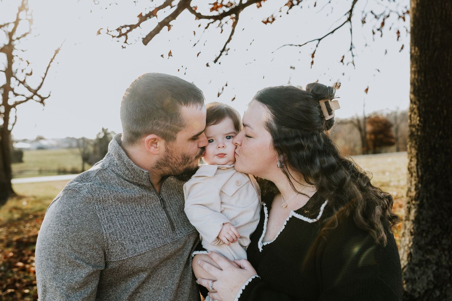 Family session, mom and dad kissing baby on cheek