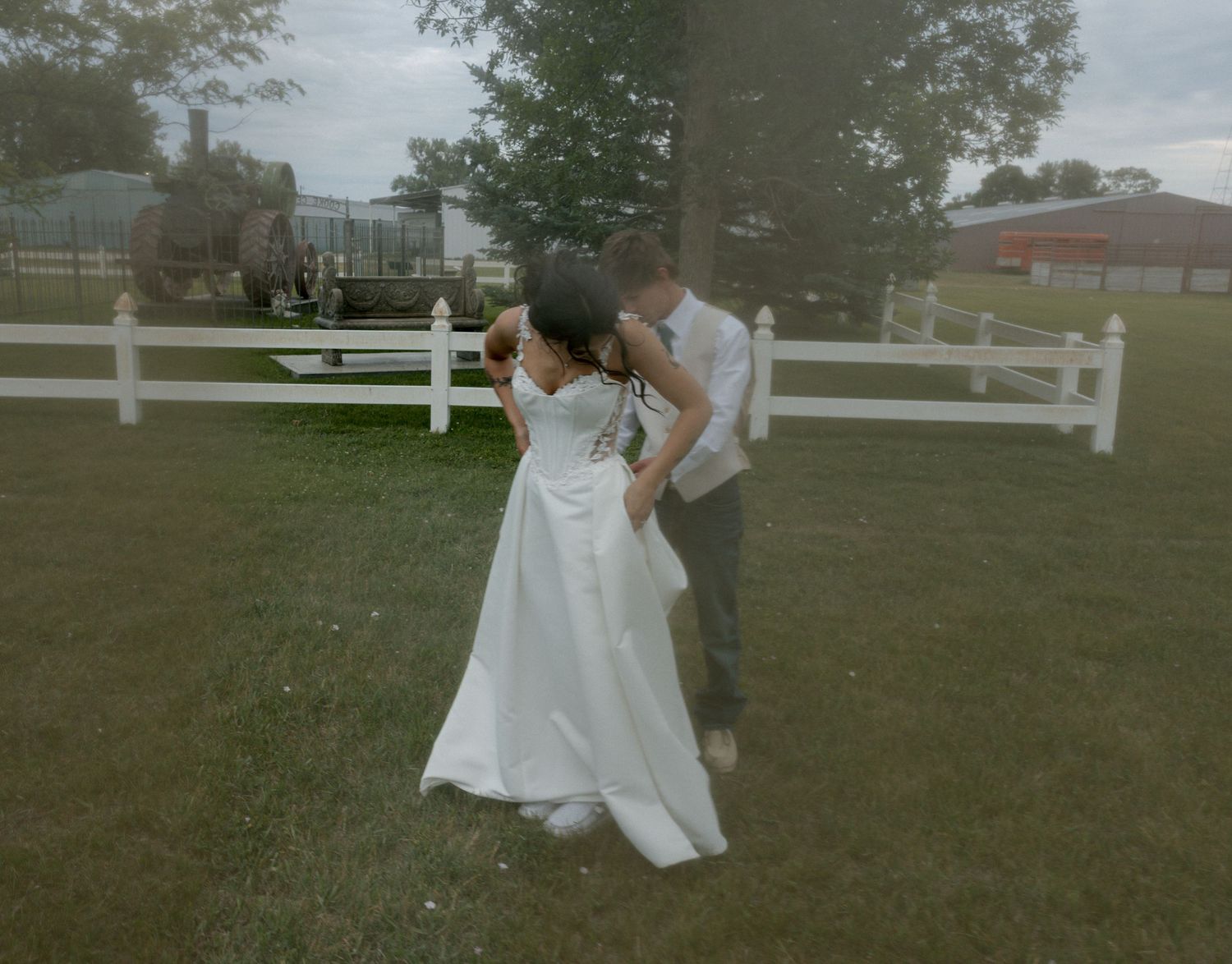 Bride and groom sharing a romantic dance outdoors near a white fence on their wedding day.
