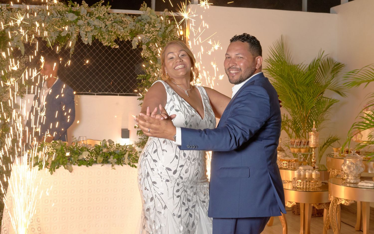 Newlywed couple dancing together with sparkling fireworks backdrop at wedding reception.