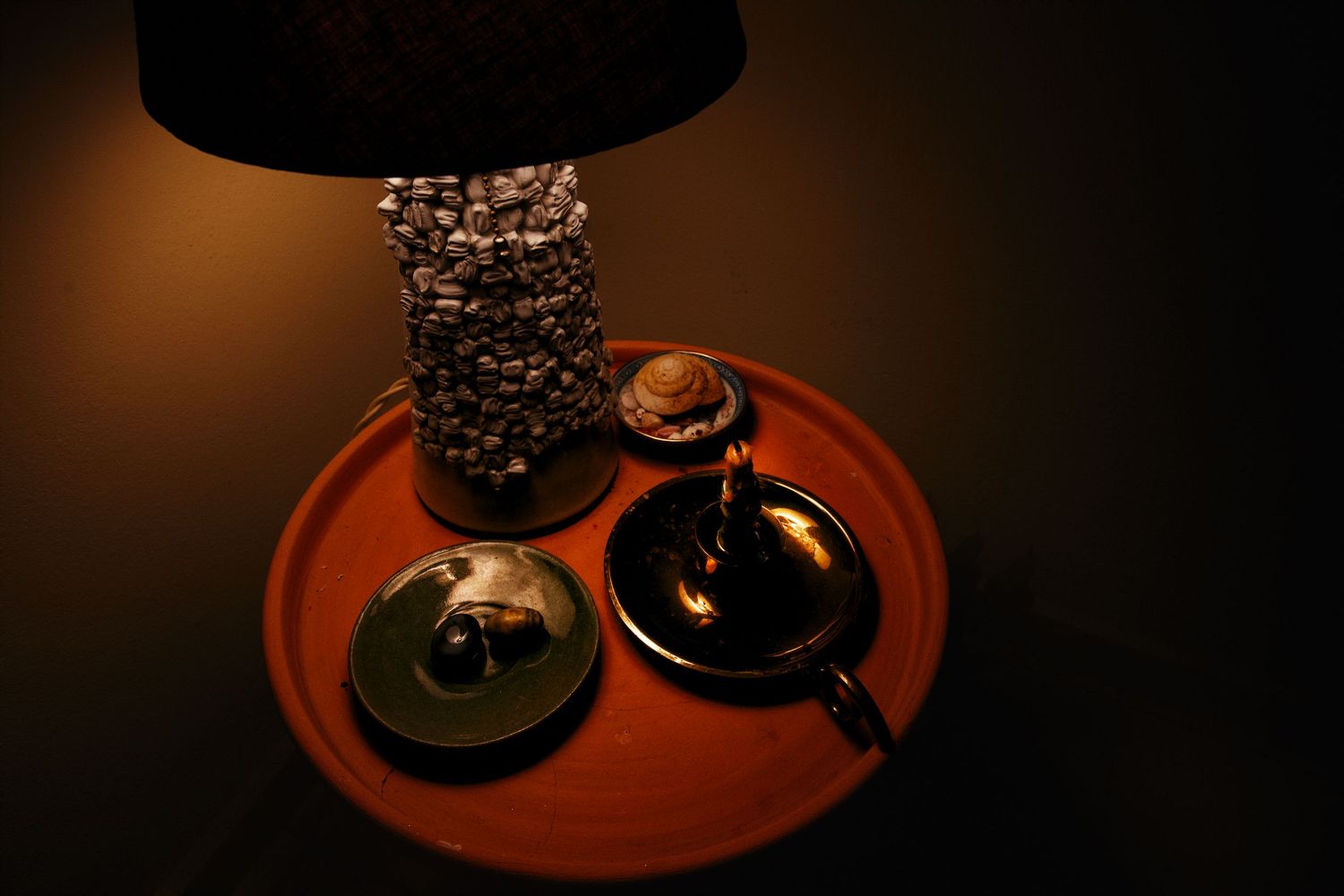 Decorative stone lamp on tray with small objects in warm dim lighting.