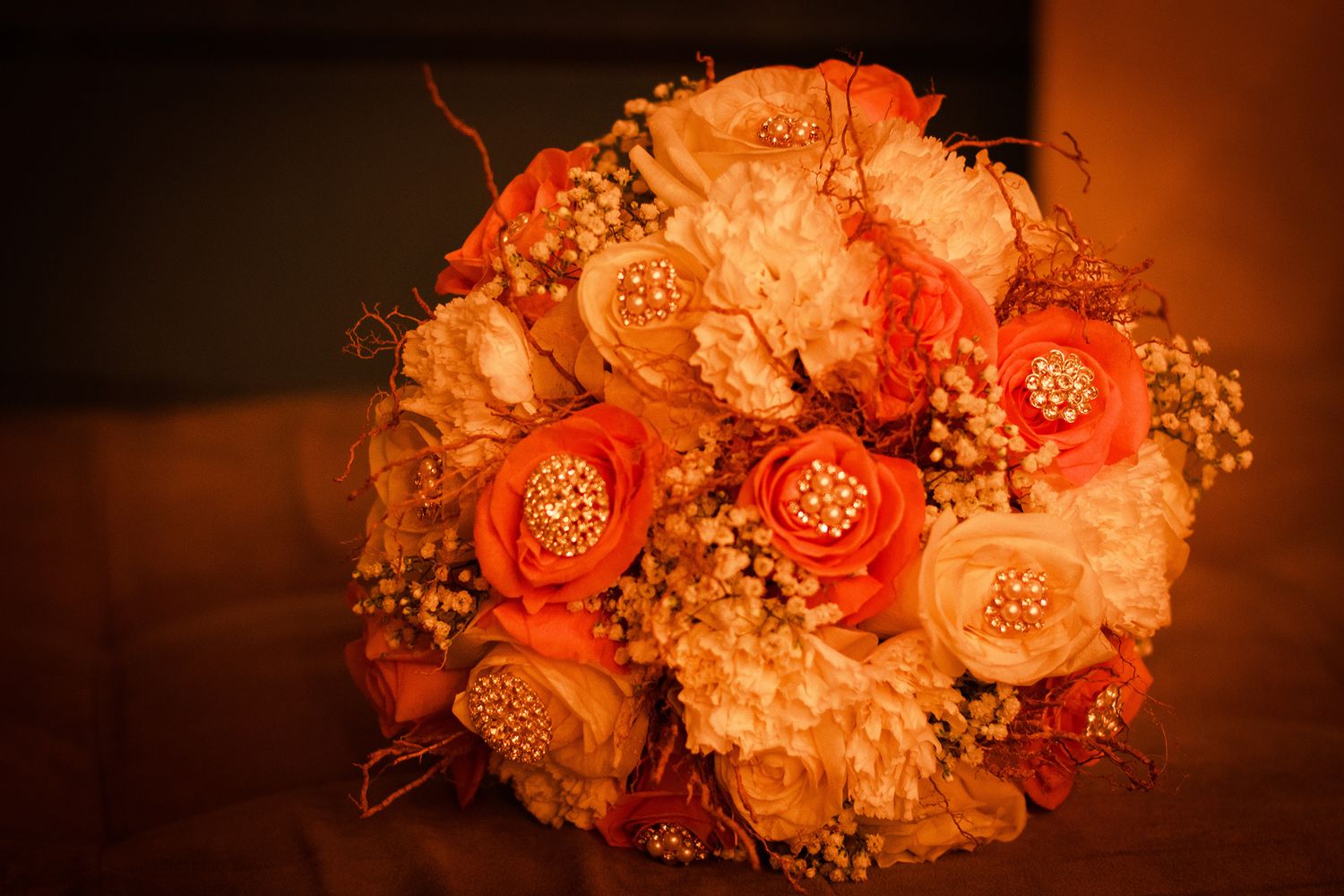 Elegant orange and white wedding bouquet with gold brooch accents and baby breath flowers.
