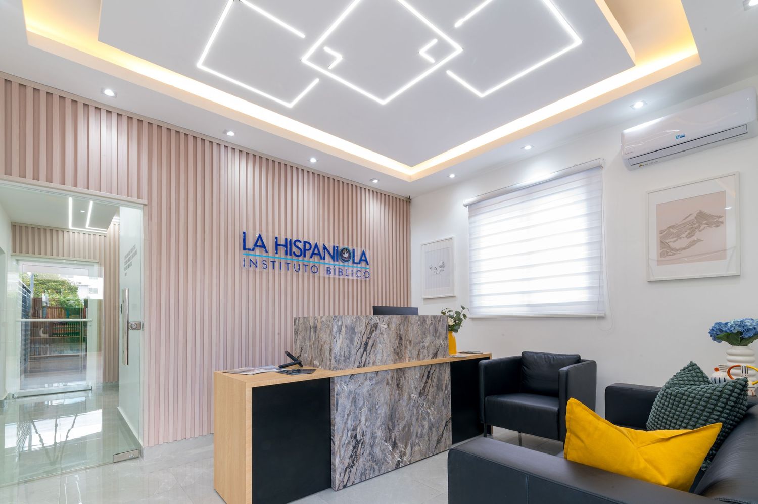 Modern La Hispaniola office reception area with marble desk, geometric ceiling lights, and contemporary decor.