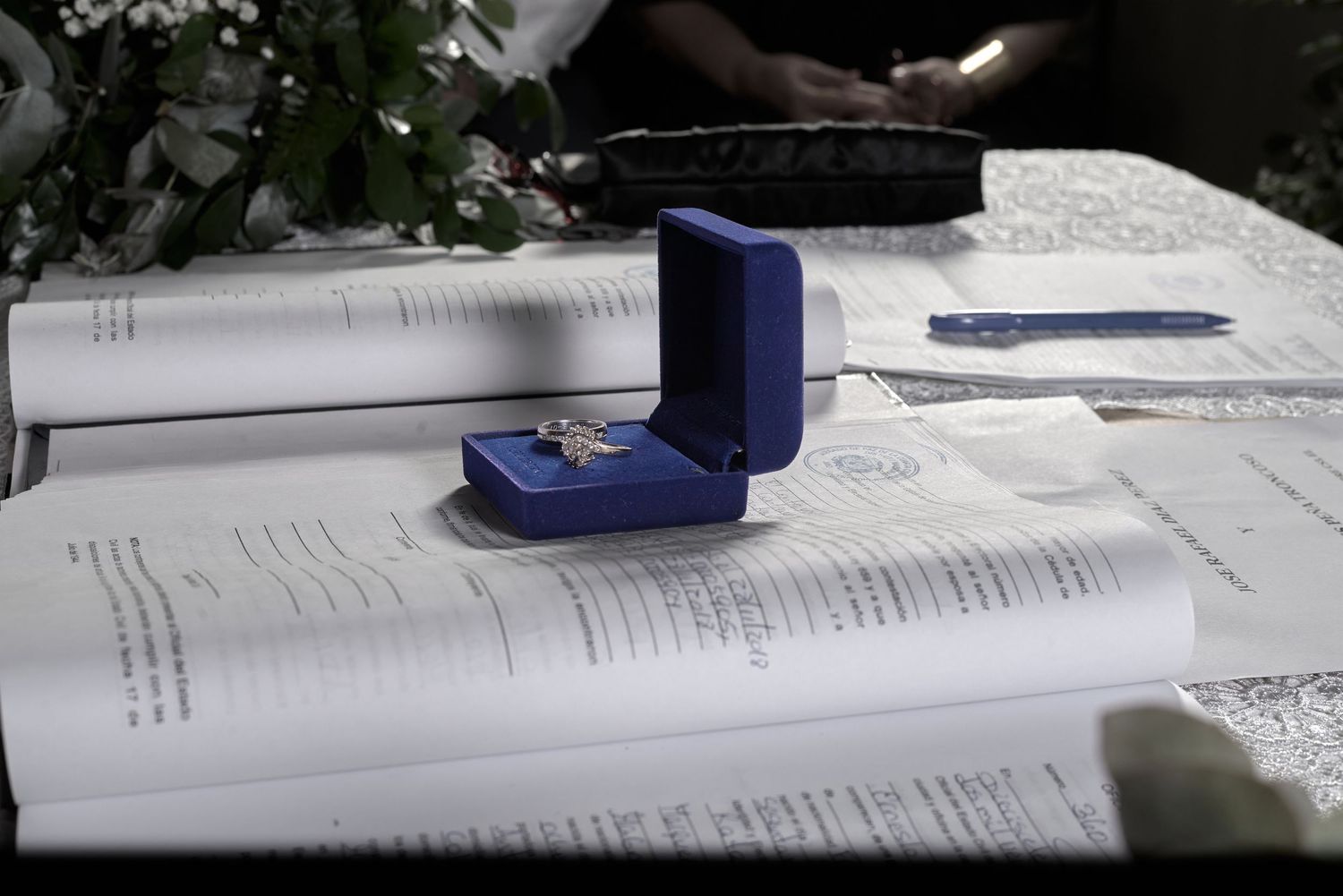 Wedding rings in blue velvet box displayed on open ceremony documents at altar table.
