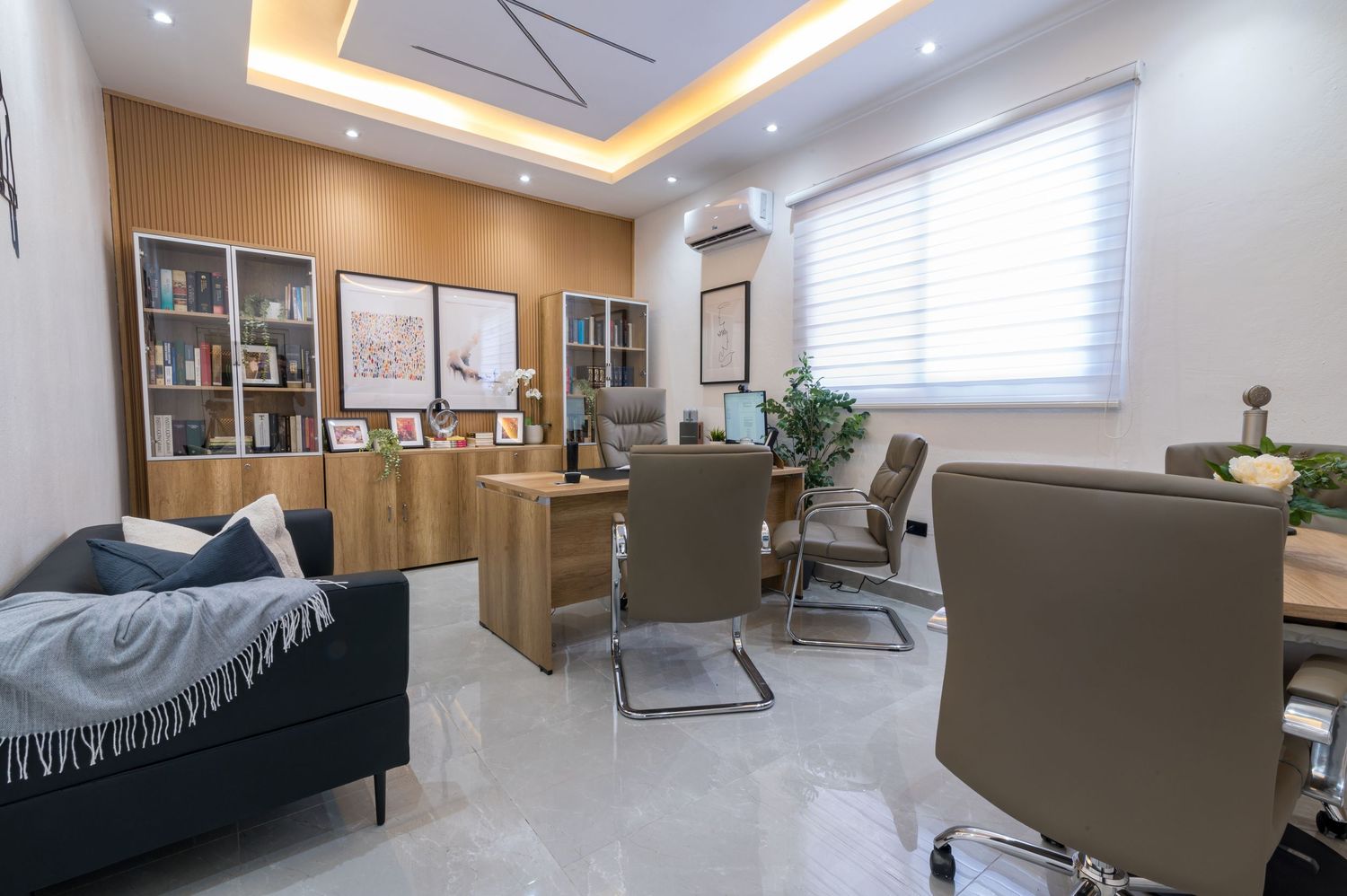 Modern office interior with warm wood accents, designer ceiling lights, executive desk, and contemporary furniture.