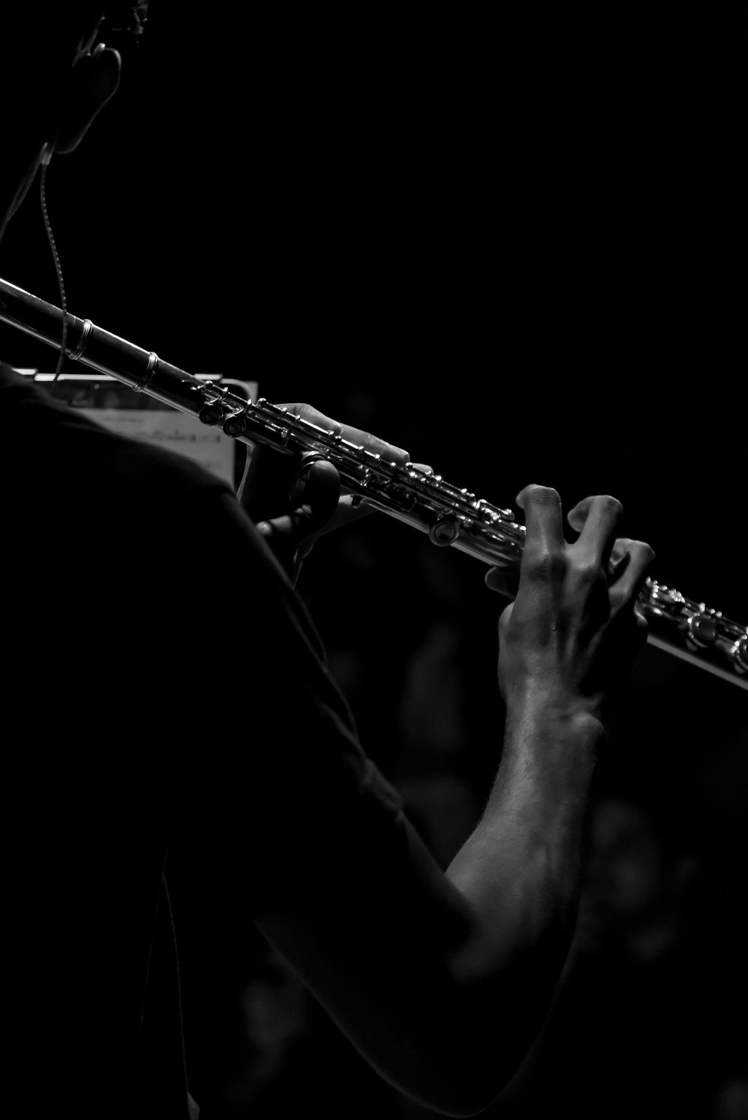 Close-up black and white photo of hands playing a soprano saxophone on stage.