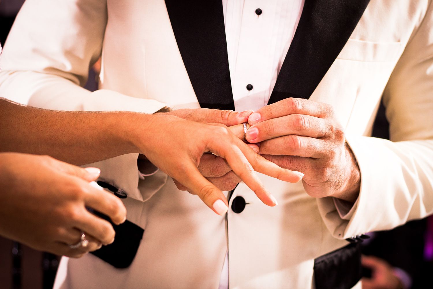 Groom placing wedding ring on brides finger during ring exchange ceremony close-up.