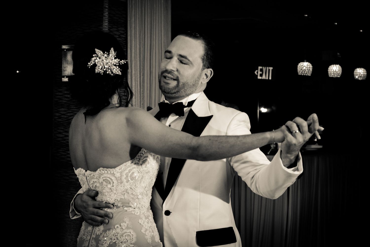 Black and white photo of bride and groom sharing romantic first dance at wedding reception.