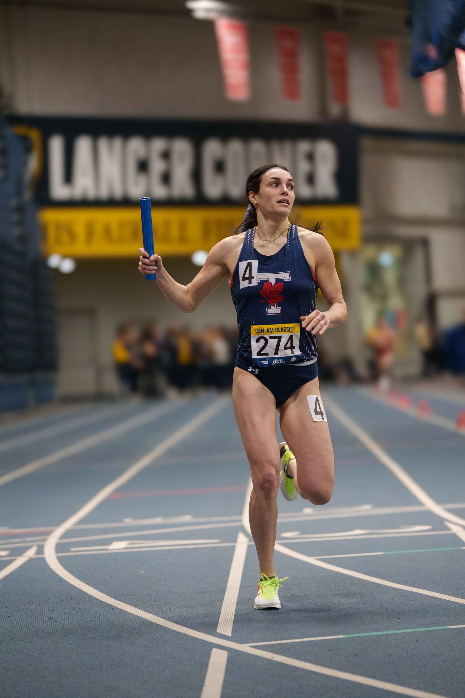 A young female relay runner finishing the last leg with her baton arm held high.