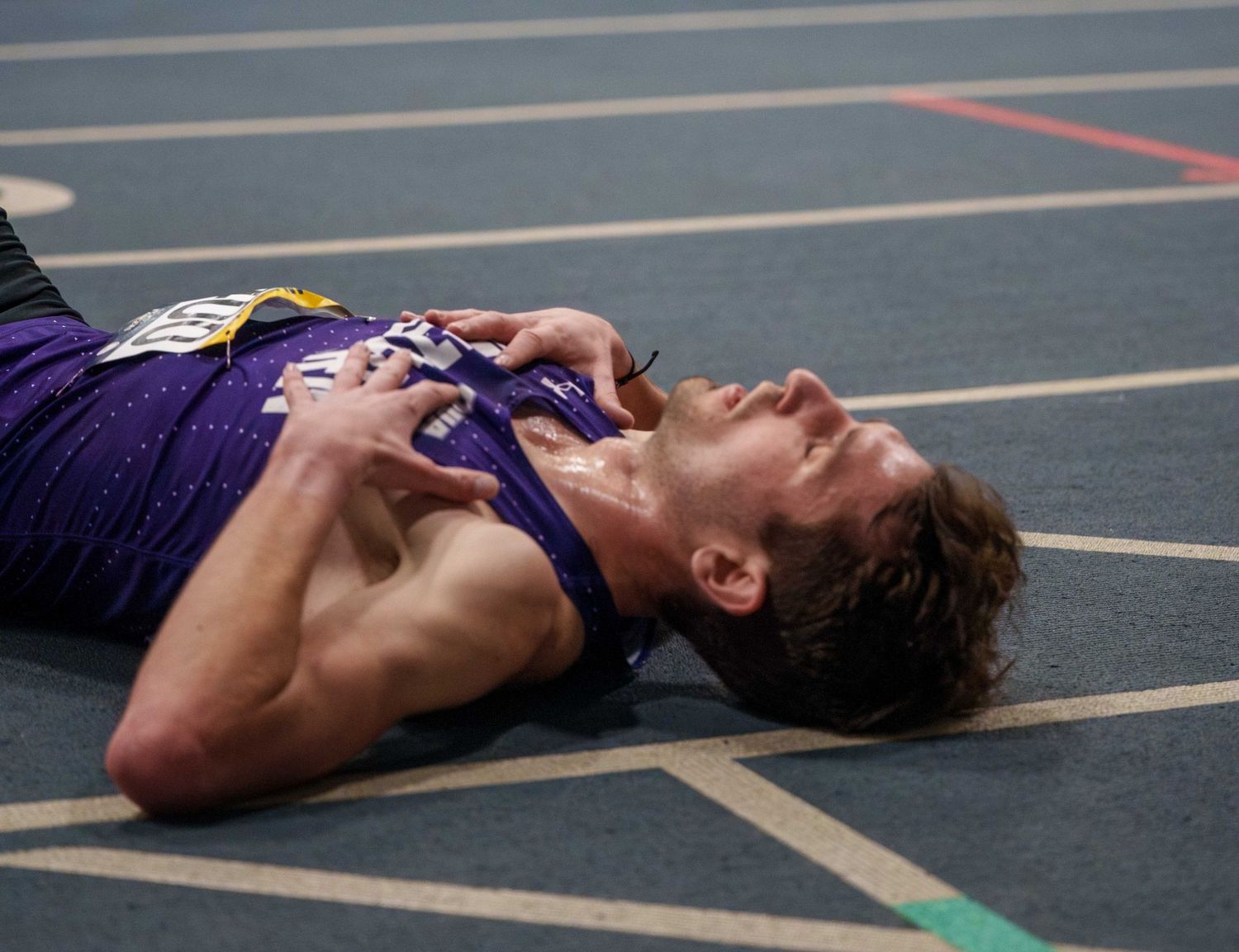 Male track runner collapsed on the track.