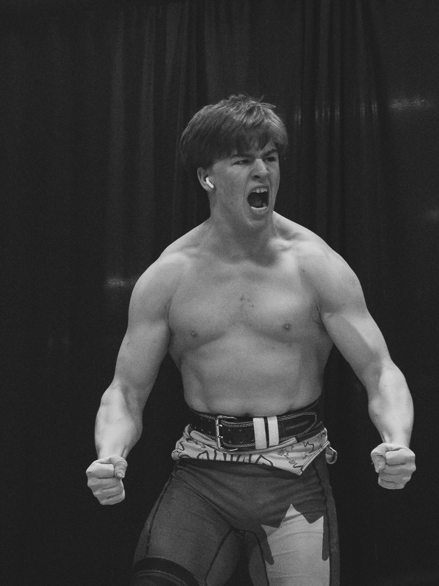 Young white male weightlifter with no shirt yells in victory after a successful PR.