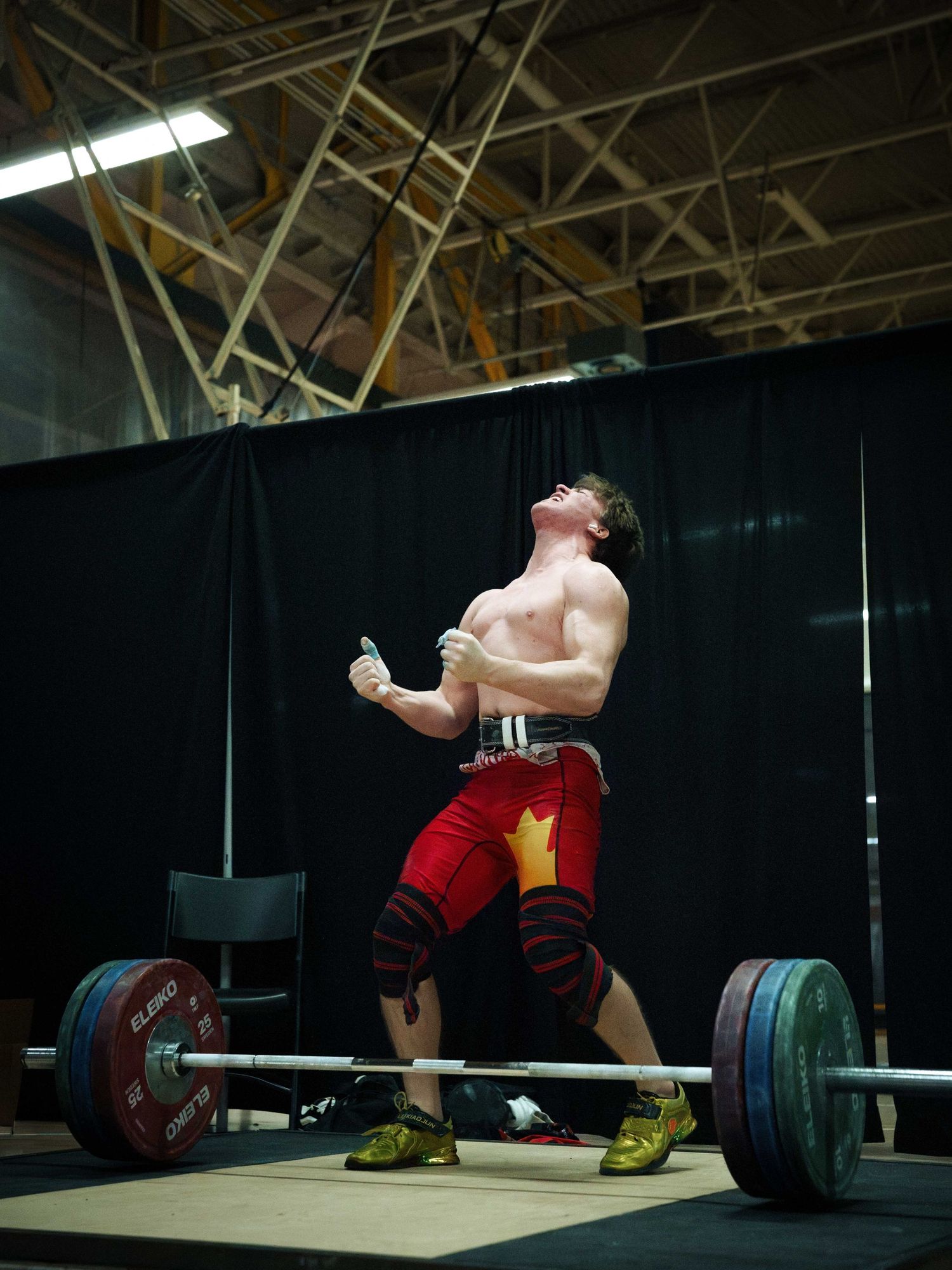 A young white male weightlifter shouts with his head thrown back in exasperation after he misses his PR attempt.
