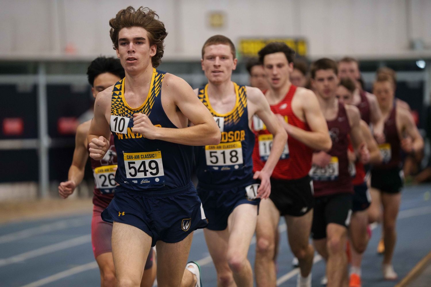 A pack of long distance track male track runners.