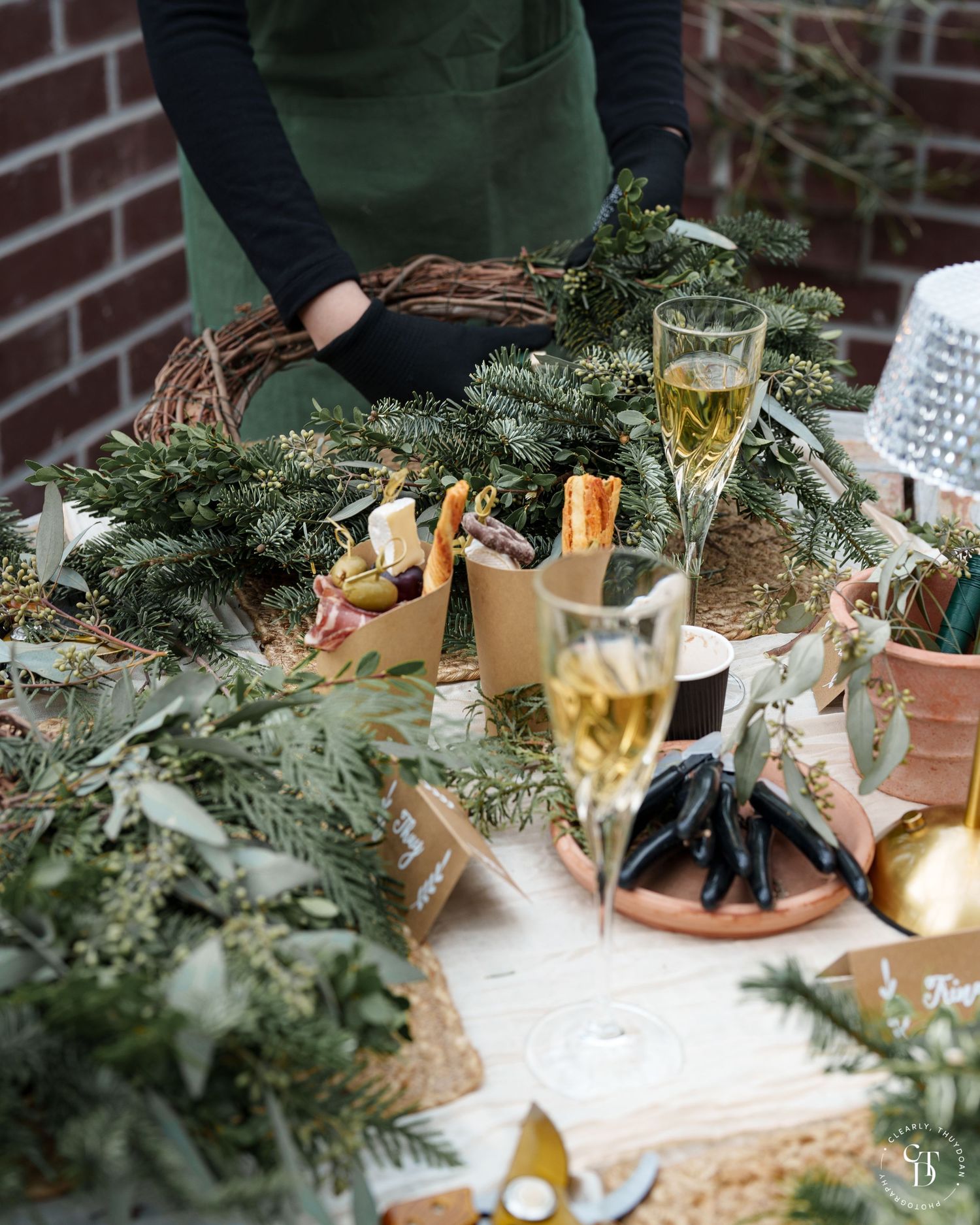 A lush green tablescape with white champagne. The table is adorned with wreath making materials.