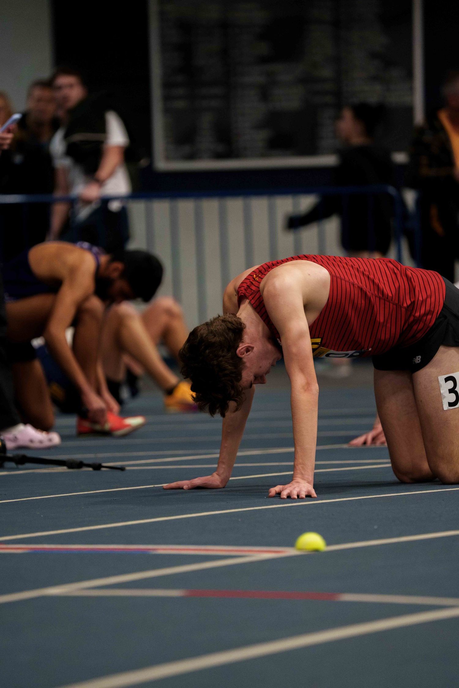 A young male track runner collapsed on all fours on the track.