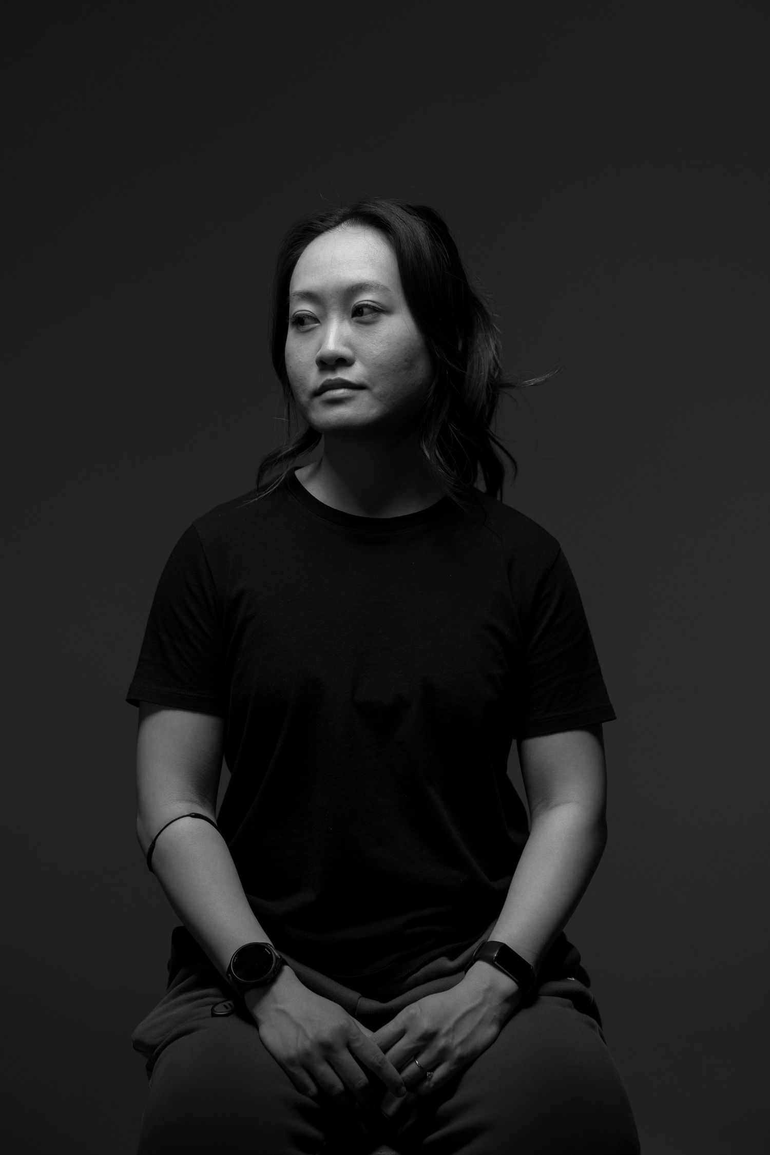 Black and white flash portrait in studio of a young Asian adult woman looking relaxed and gazing off to the side.