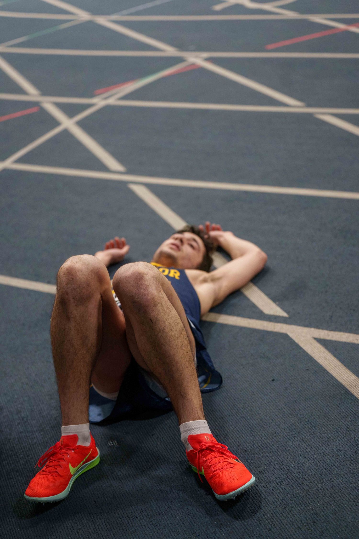 A young male track runner collapsed on his back on the track.