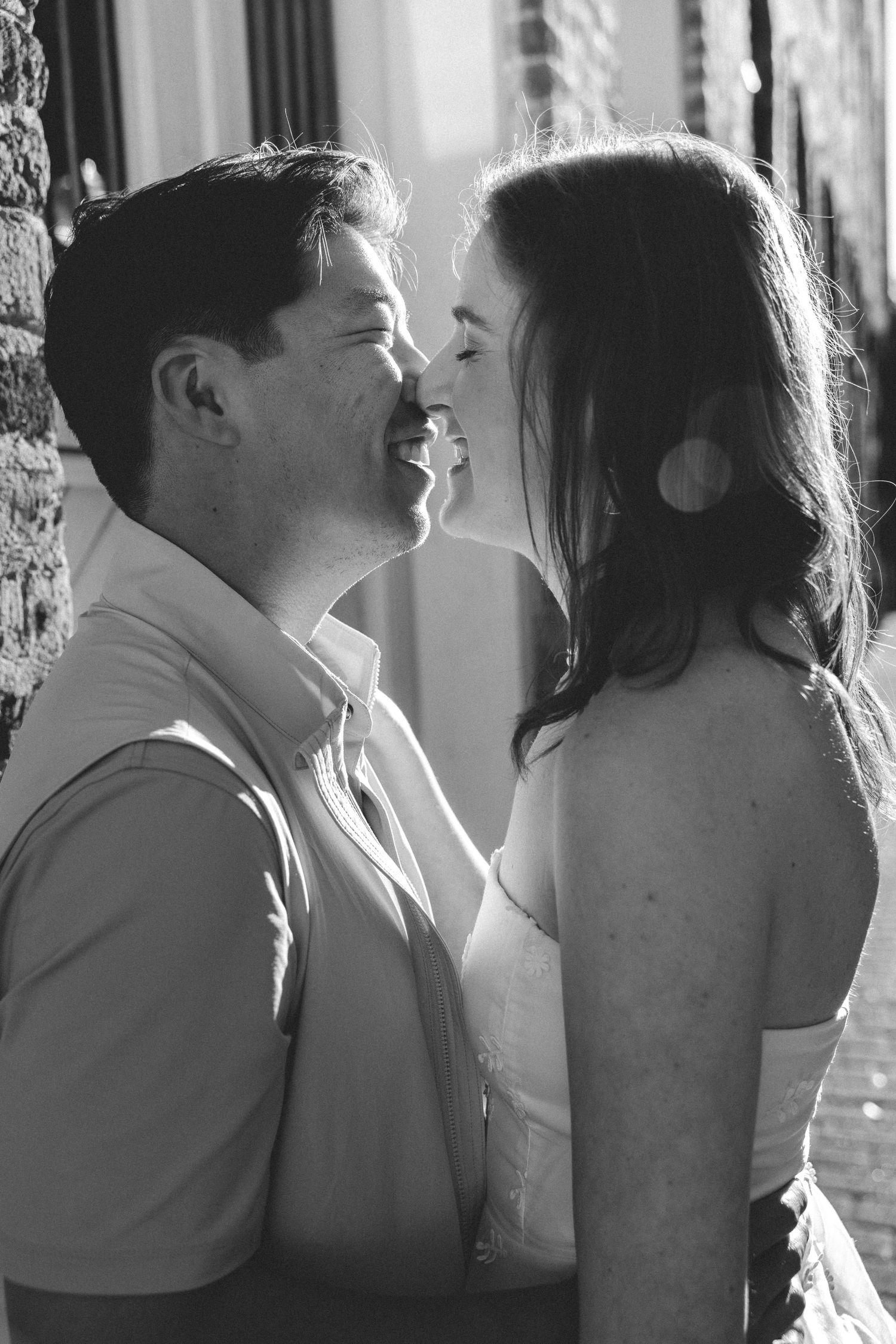 A romantic black and white portrait of a couple in an intimate close-up moment near a window.