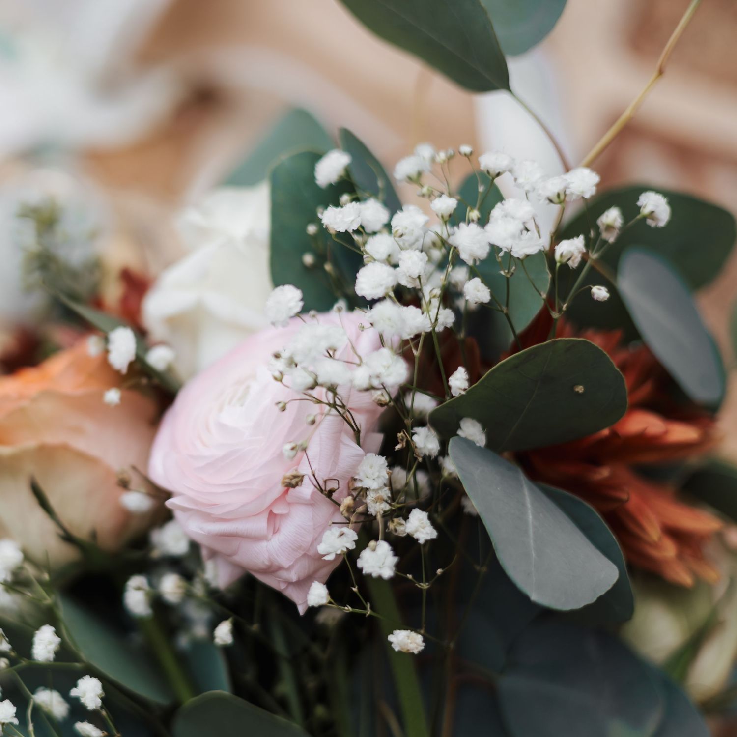 Delicate floral arrangement with pink roses, baby's breath, and eucalyptus leaves.