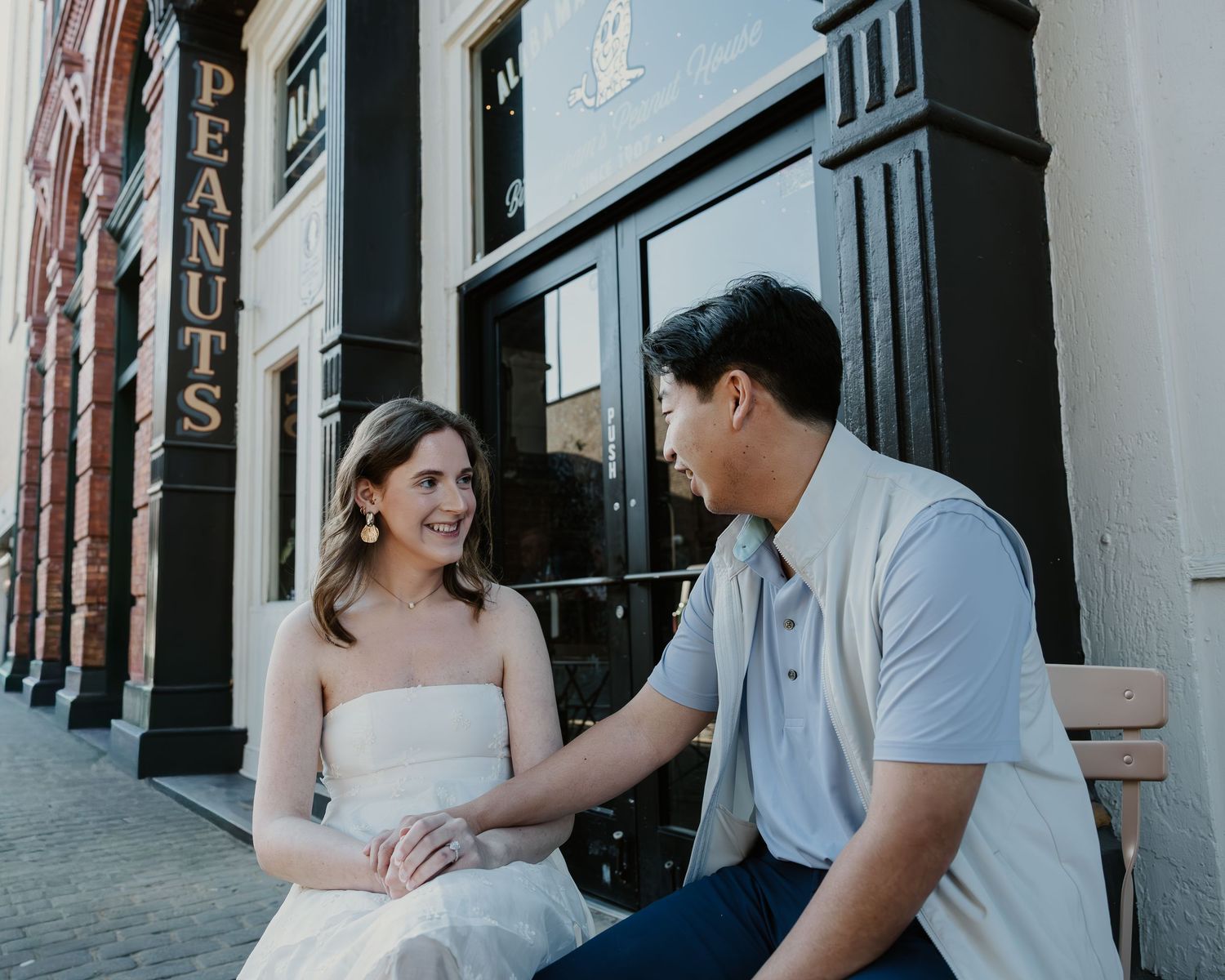 Couple sits together on outdoor steps during a romantic engagement photo session in black and white.