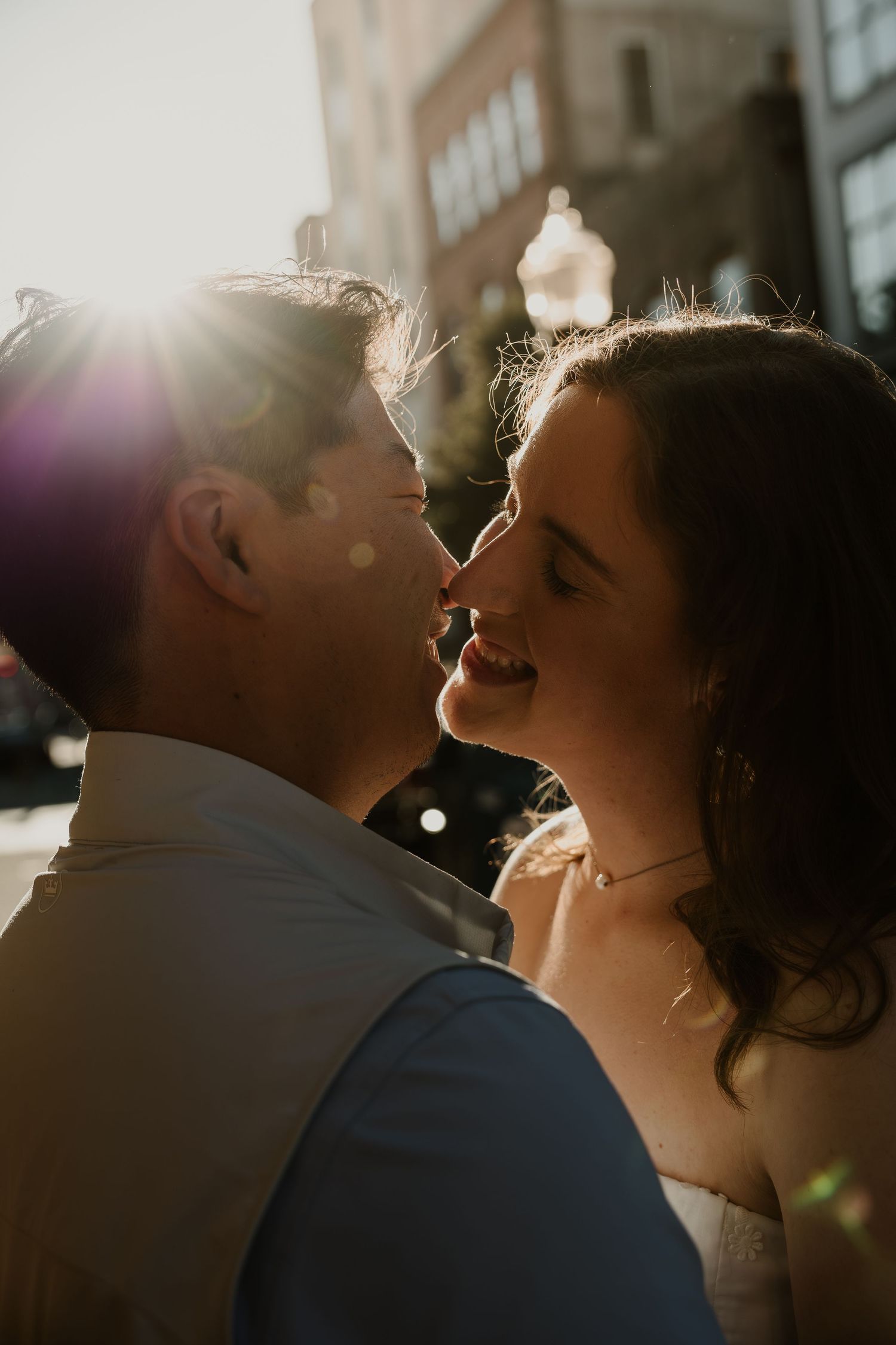 A couple shares an intimate moment in warm sunlight during their wedding day celebration.