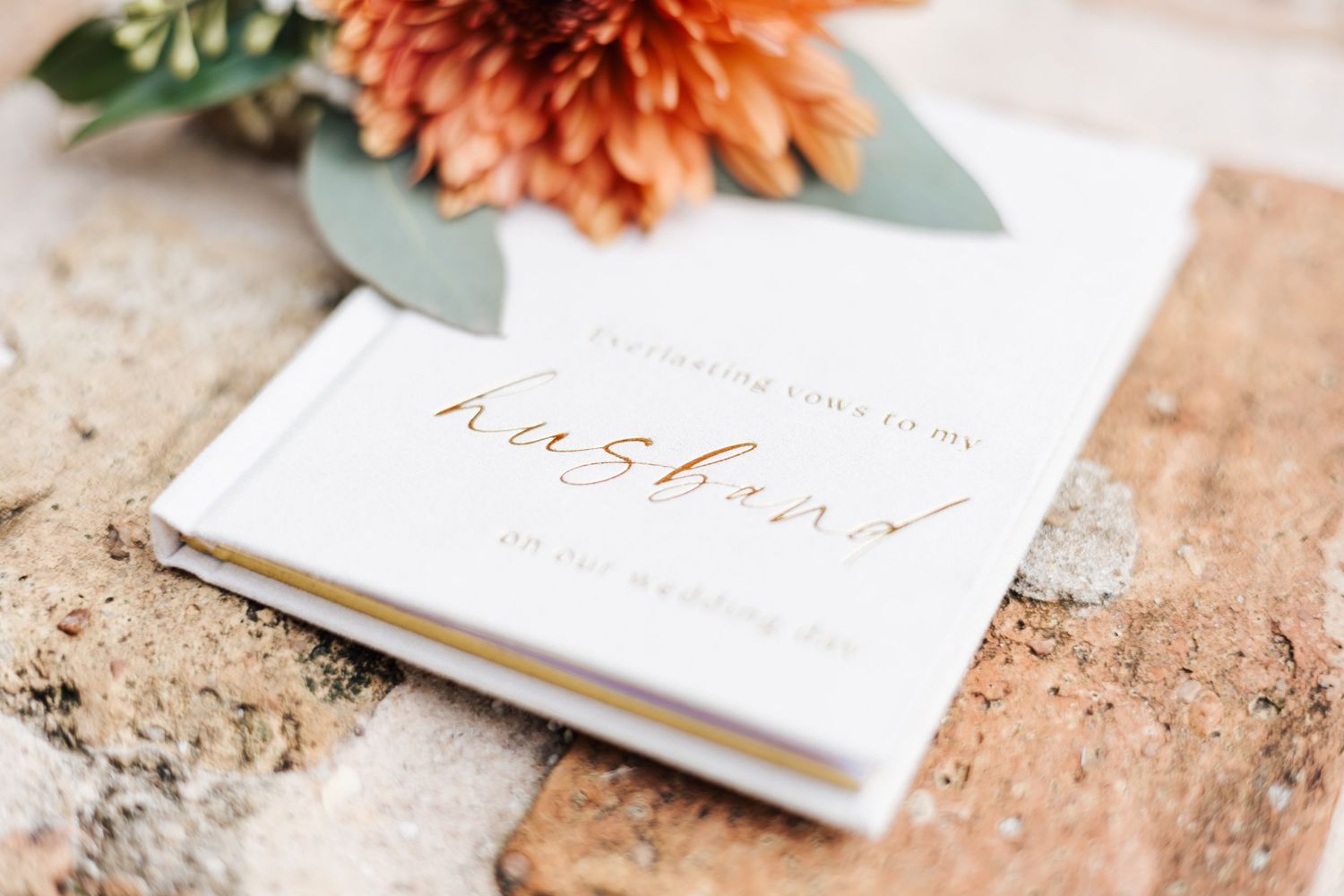 Wedding invitation suite with coral flowers and greenery on a textured background.