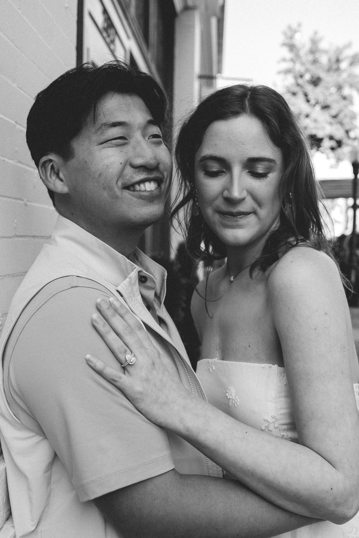 A black and white portrait of a happy couple embracing outdoors on a sunny day.