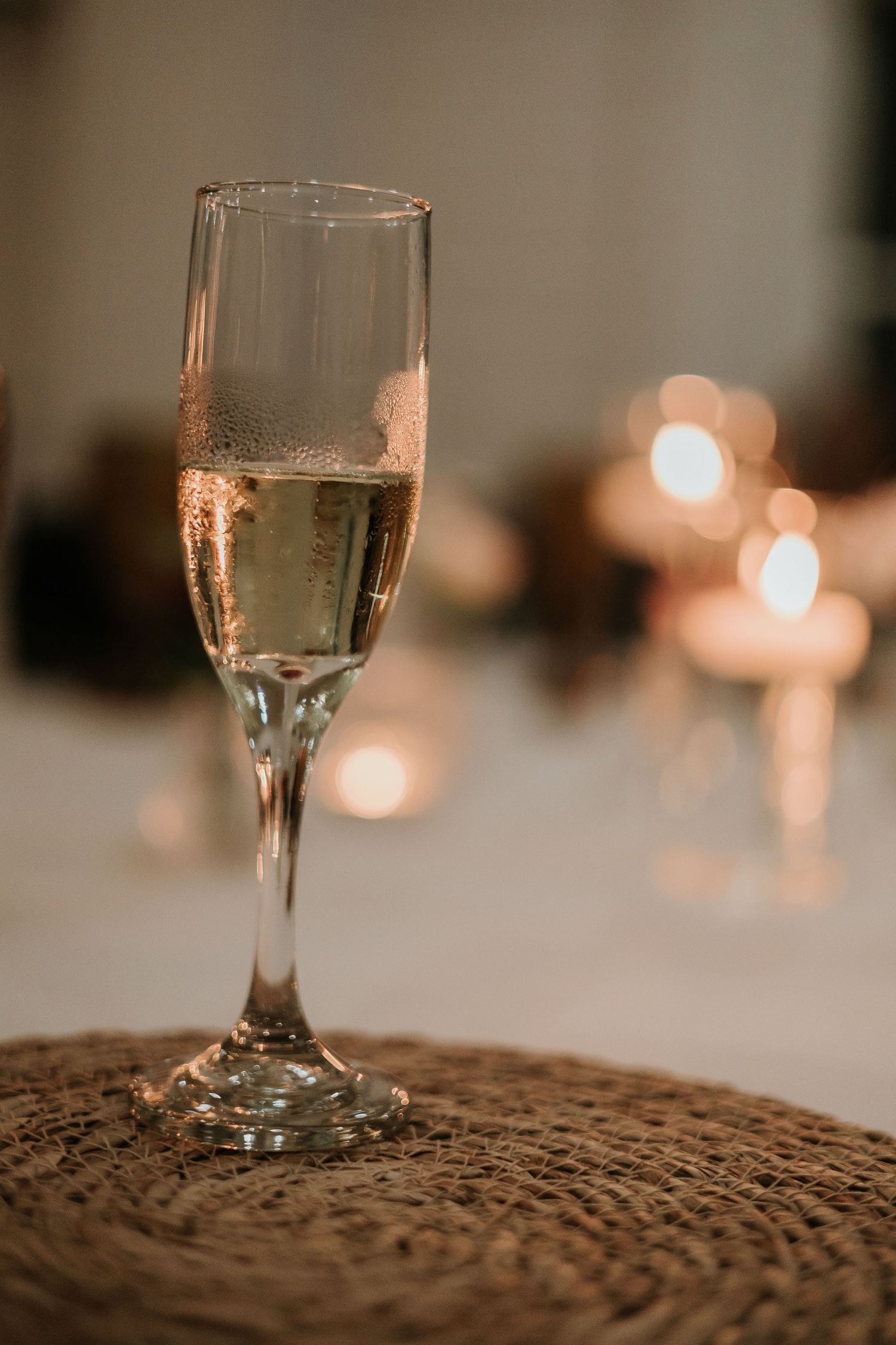 Wine glass with champagne on textured surface with soft bokeh lights in background.