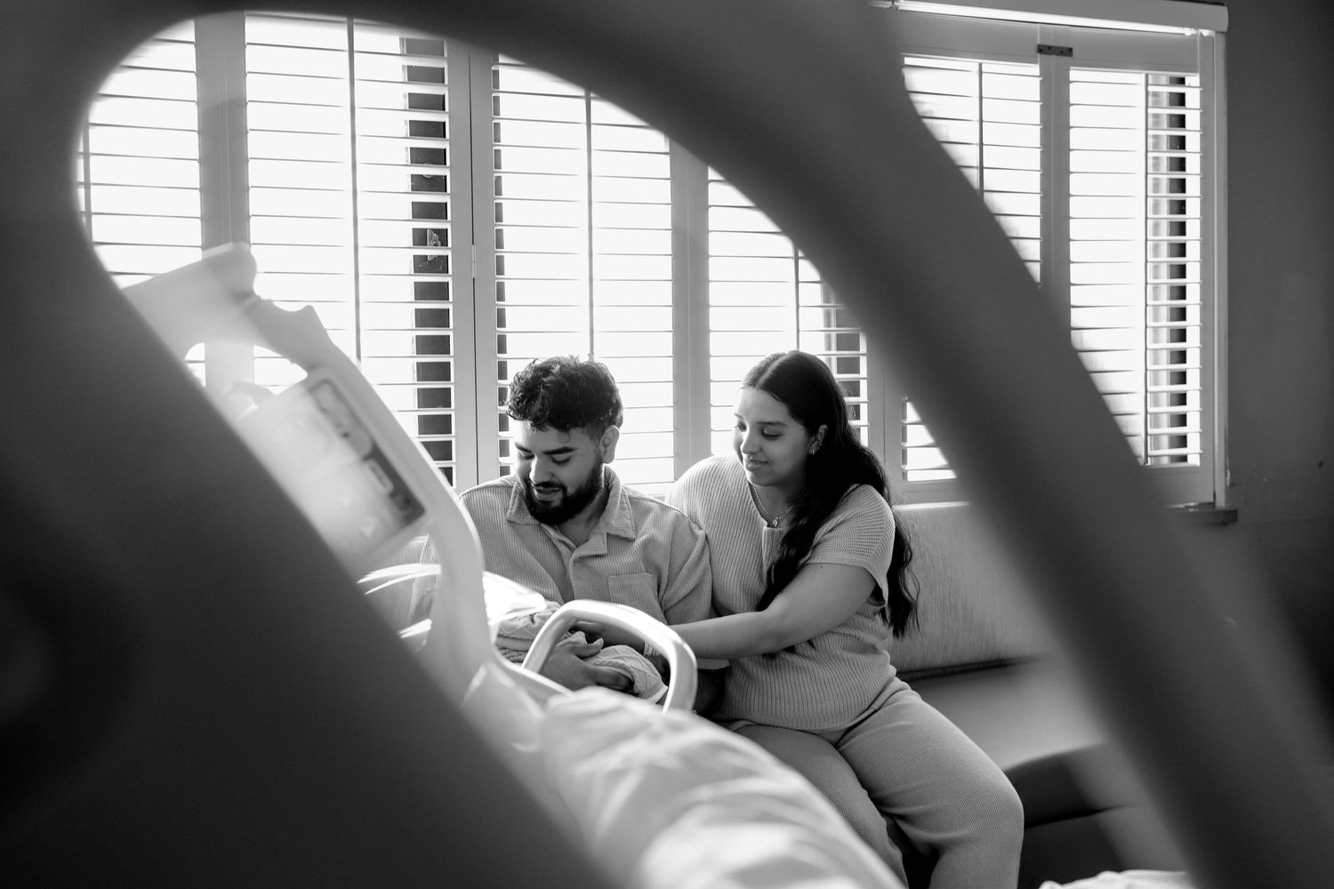 Couple bonding with newborn in hospital room, black and white photo.