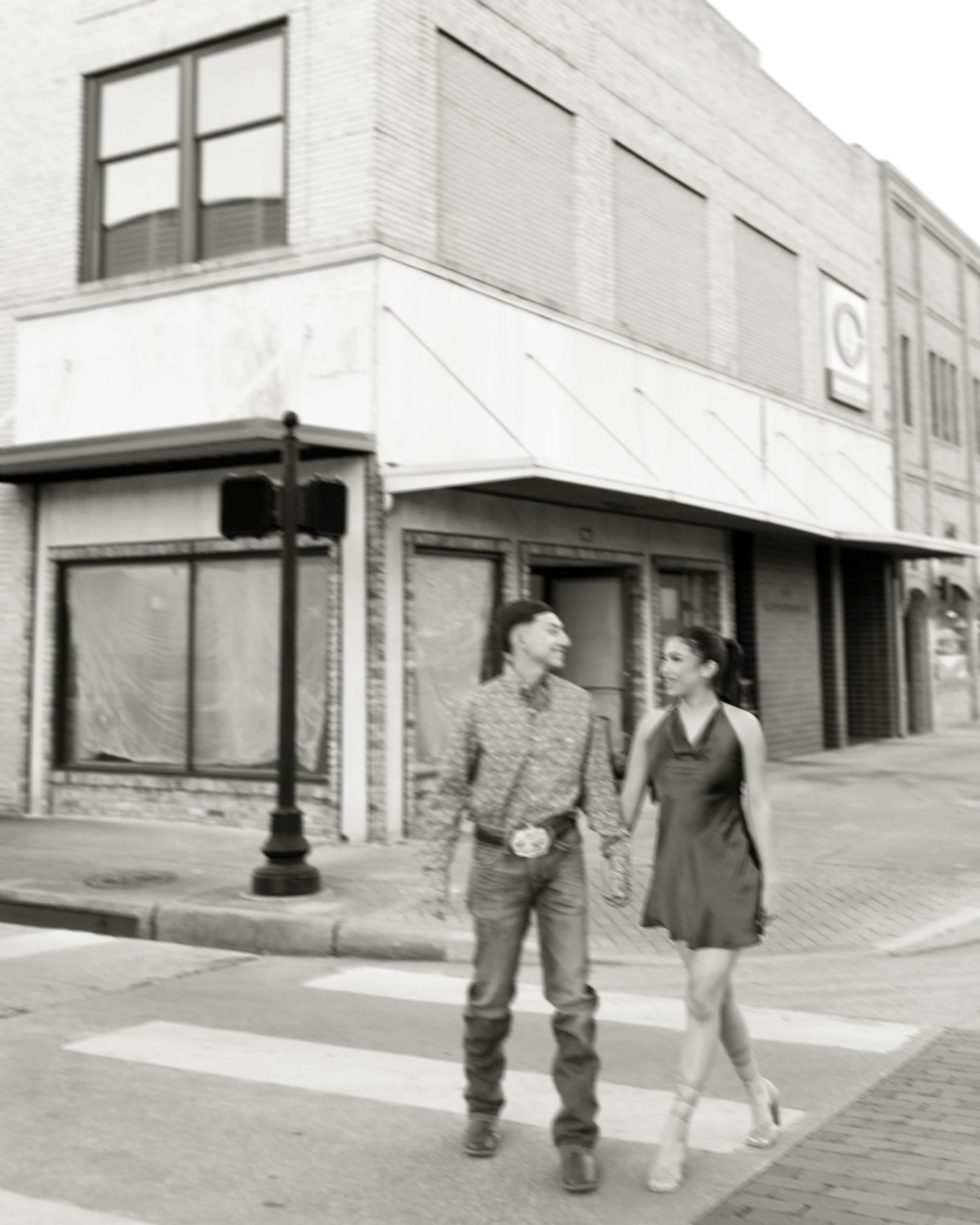 Black and white photo of couple holding hands crossing a downtown street.