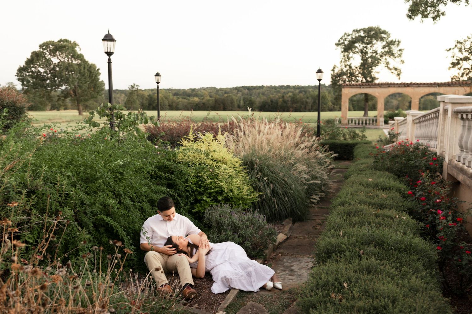 Couple sitting together in a beautiful garden reading at dusk.