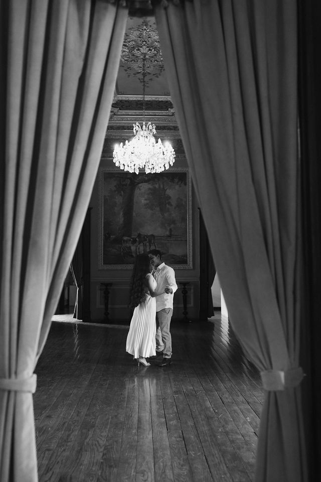 Black and white bridal portrait in Tyler, Texas featuring a bride framed by elegant curtains in a timeless indoor wedding setting.