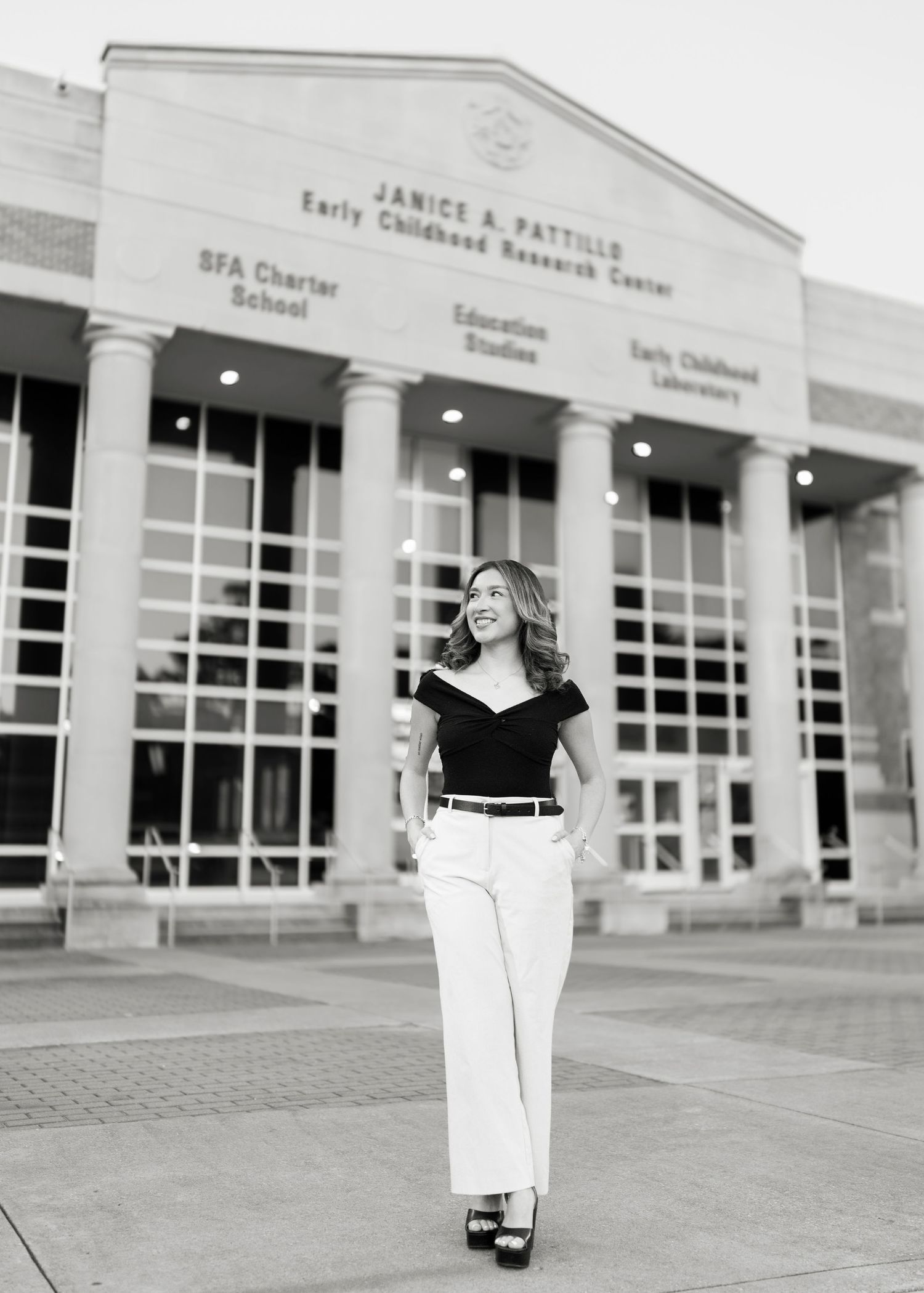 Black and white portrait of a woman in white pants and black top standing before Janice A. Pattillo Center.