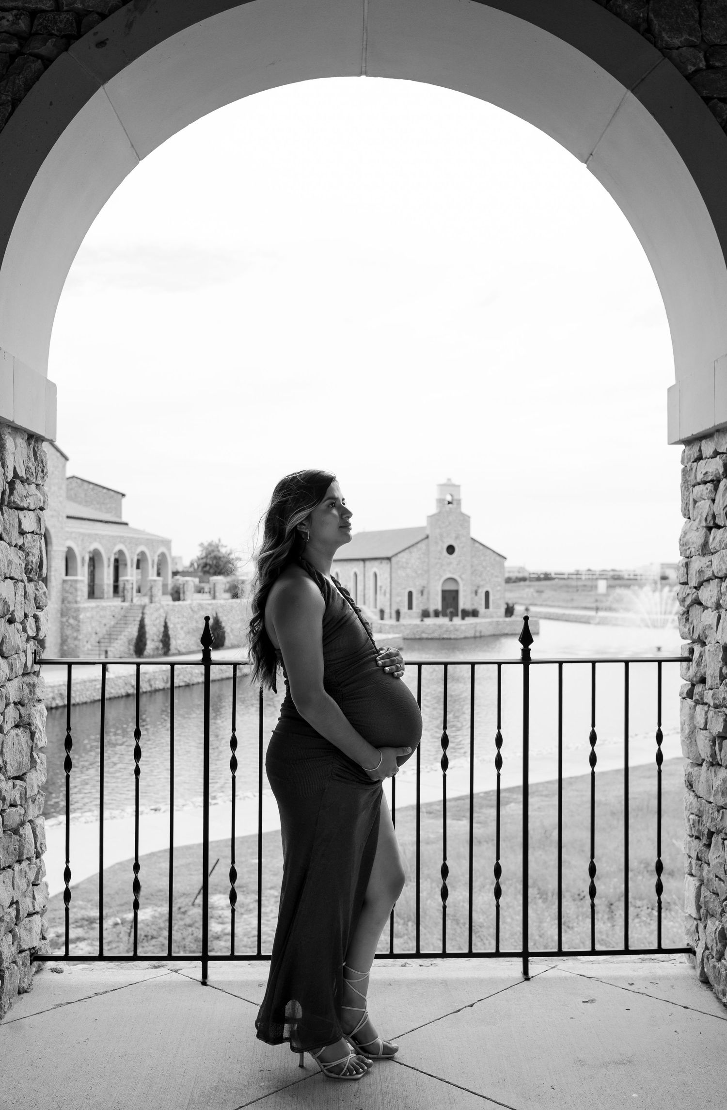 Couple standing under an arched walkway in Europe, romantic destination engagement session captured with timeless photography style
