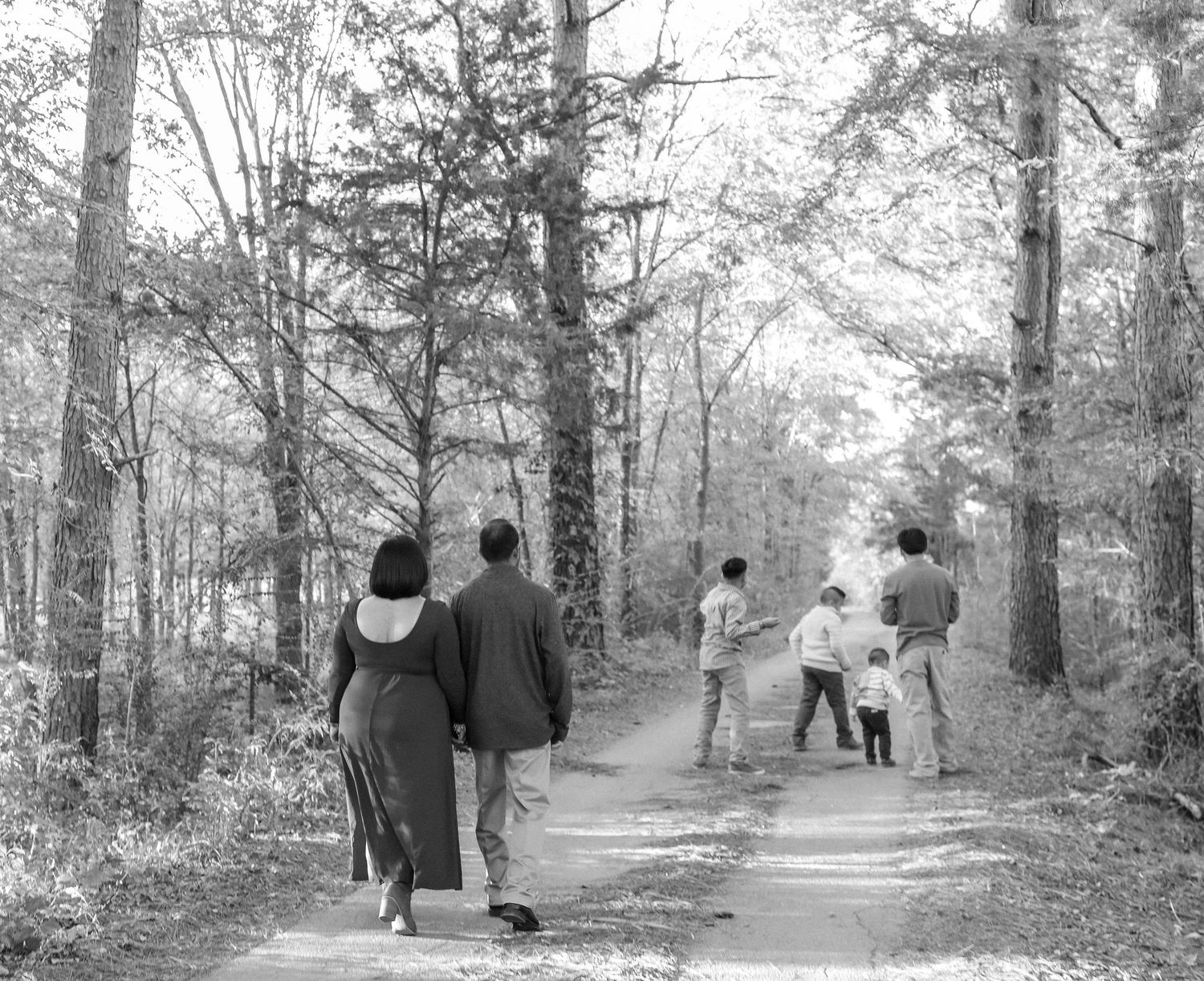 Family walking together on a wooded path in black and white.