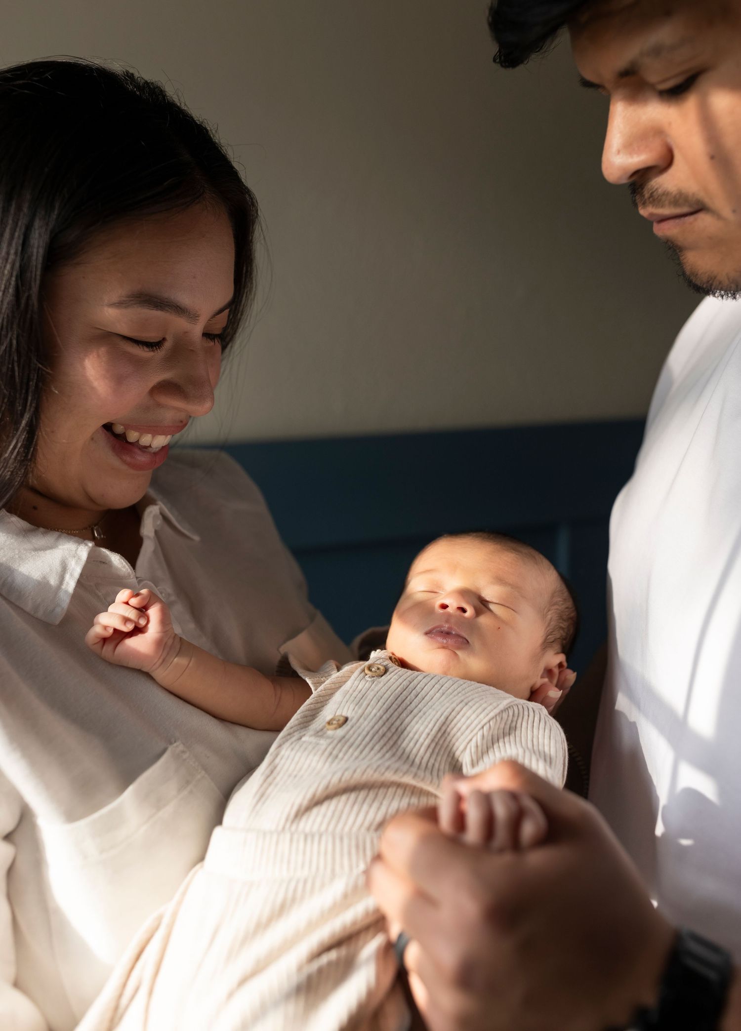 Lifestyle newborn and family photography session in East Texas capturing parents holding their baby in a soft, natural indoor setting.
