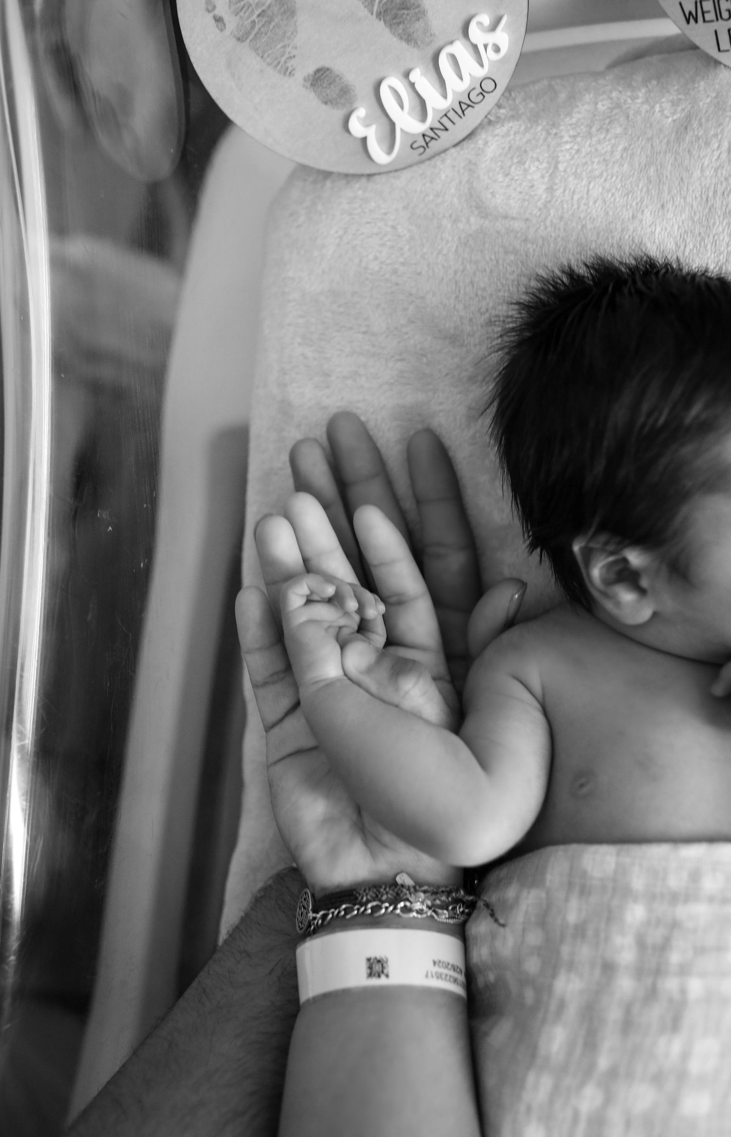 Newborn baby Elias Santiago with parent's hand in black and white.